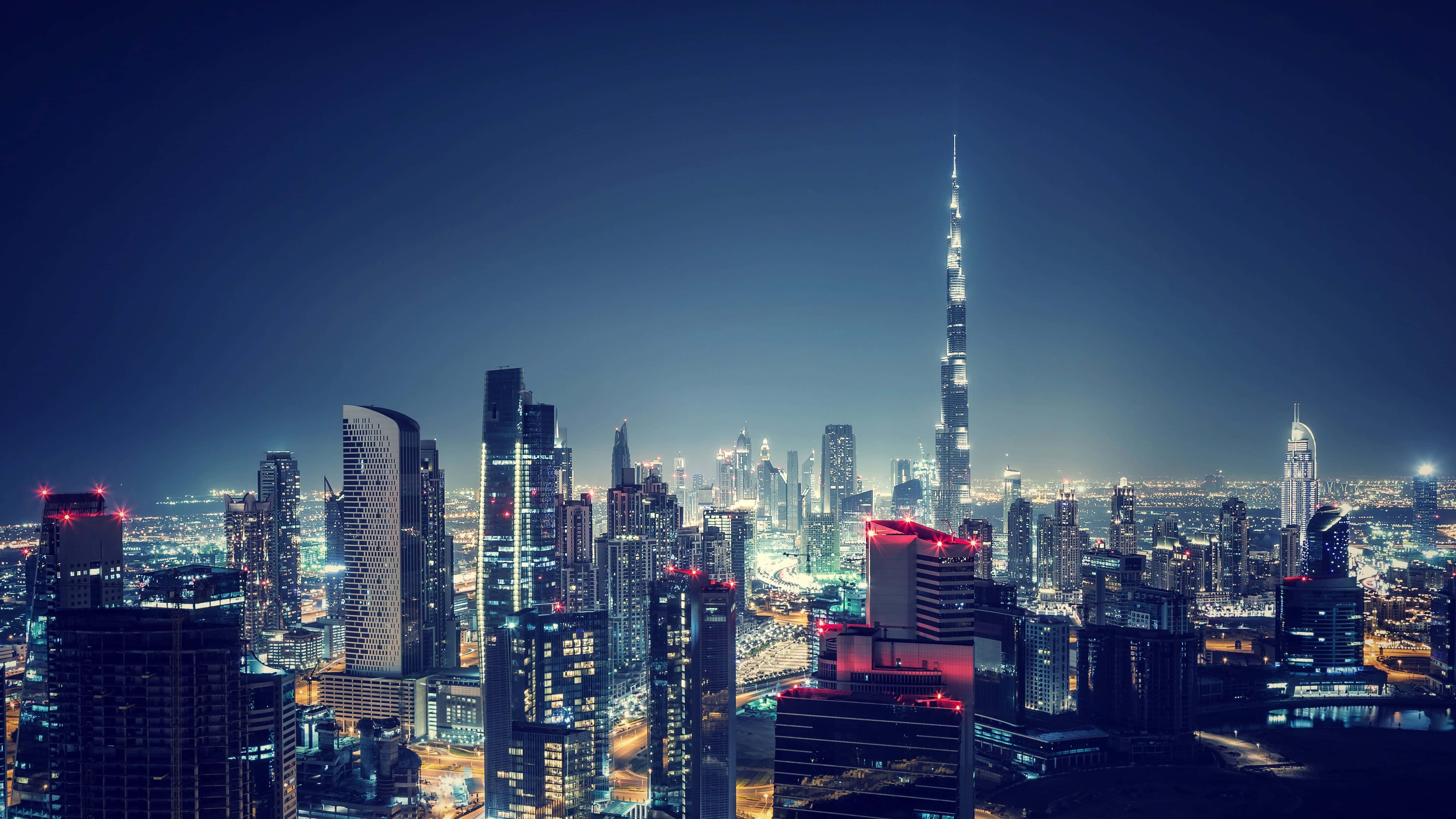 Uae 桌布 壁紙 — 杜拜令人目眩的夜景，哈利法塔聳立在閃爍的摩天大樓和燈火通明的街道之上。