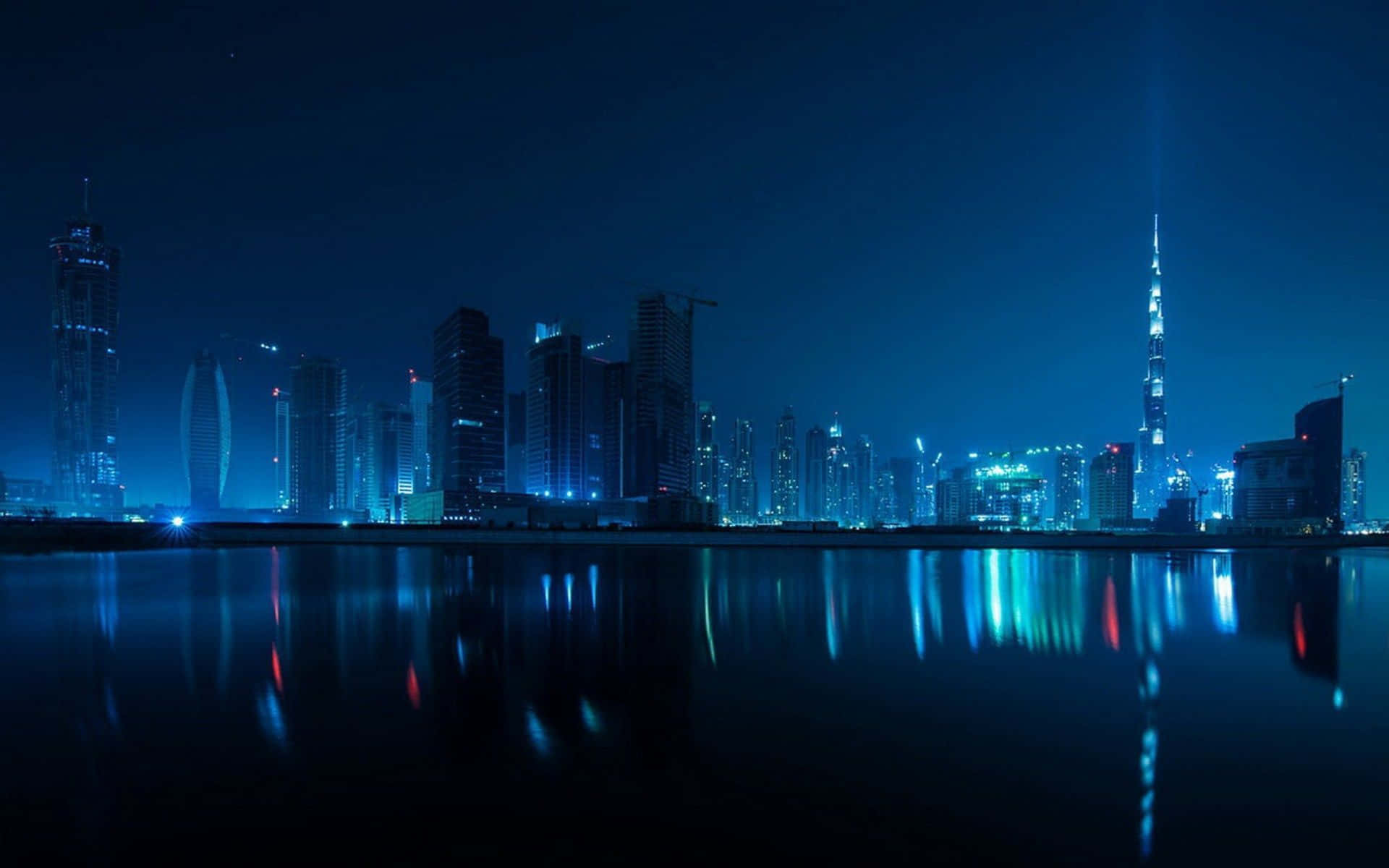 Blue Desktop 桌布 壁紙 — 杜拜令人驚嘆的夜景，燈火通明的摩天大樓和哈利法塔倒映在平靜的水面上。