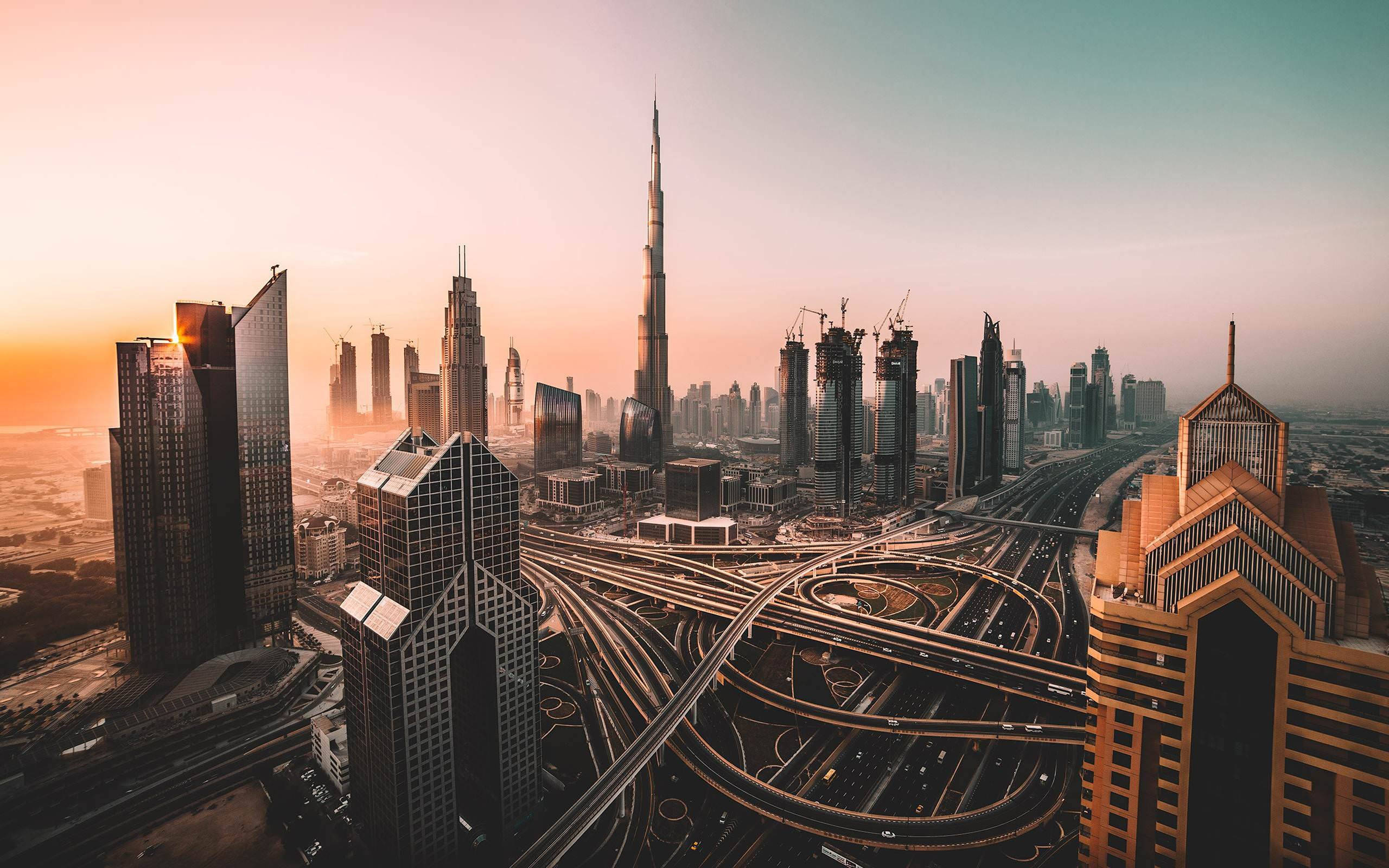Skyscraper 桌布 壁紙 — 杜拜天際線在日落時的鳥瞰圖，哈利法塔聳立在複雜的高速公路網絡和現代摩天大樓之上。