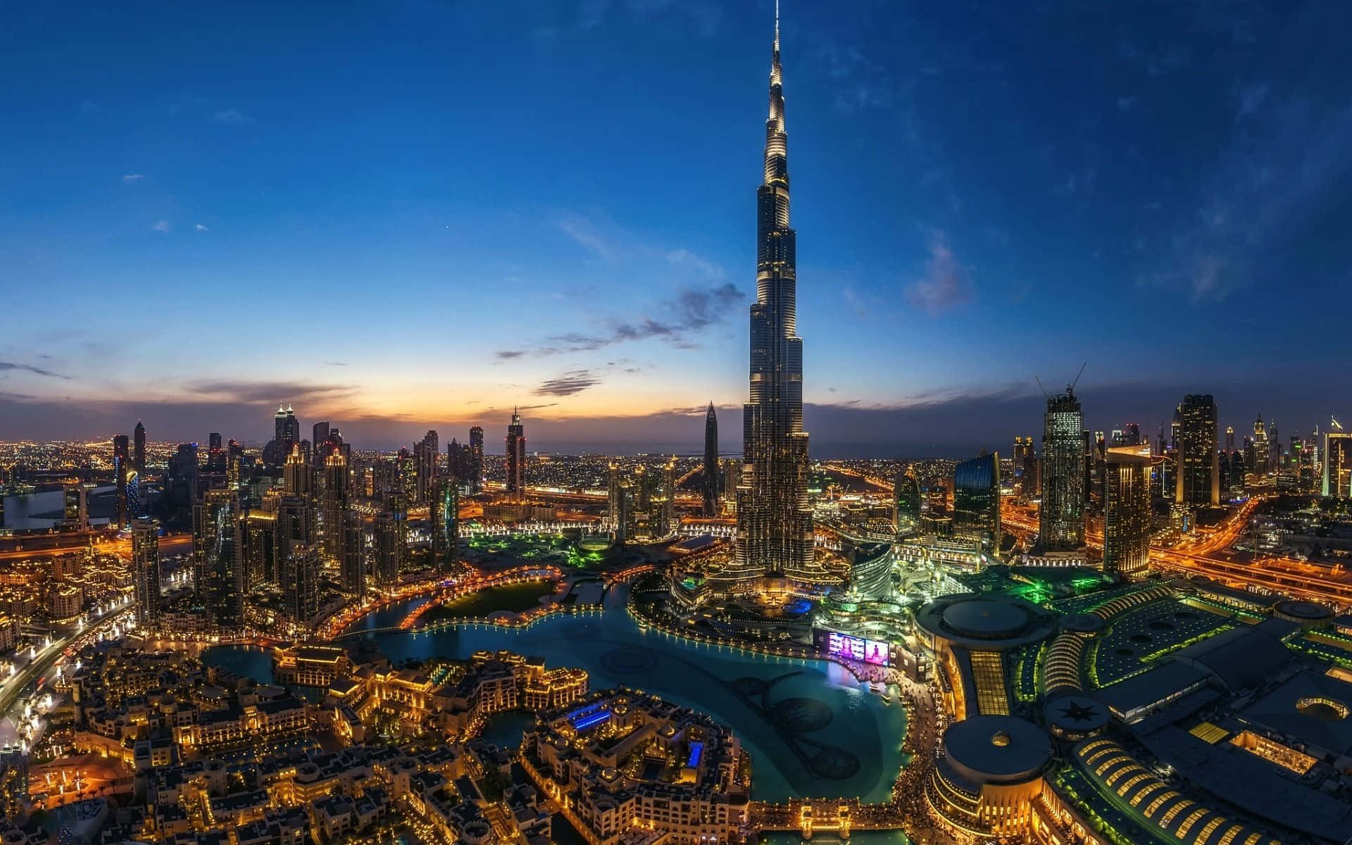 Uae 桌布 壁紙 — 杜拜天際線在黃昏時的鳥瞰圖，哈利法塔聳立於燈火通明的摩天大樓和海濱之上。