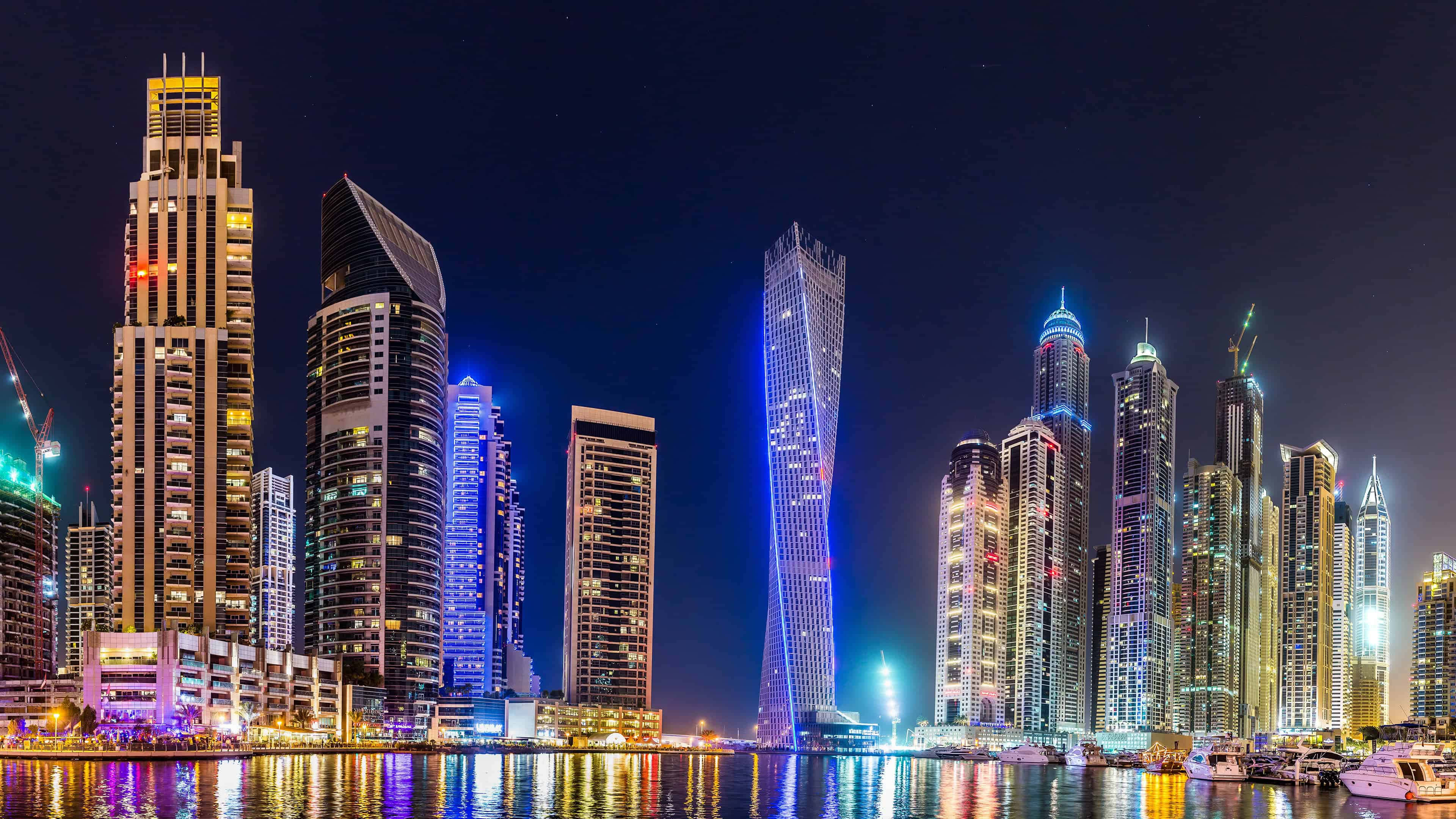 Dubai 桌布 壁紙 — 杜拜天際線的璀璨夜景，燈火通明的摩天大樓倒映在下方水面上。