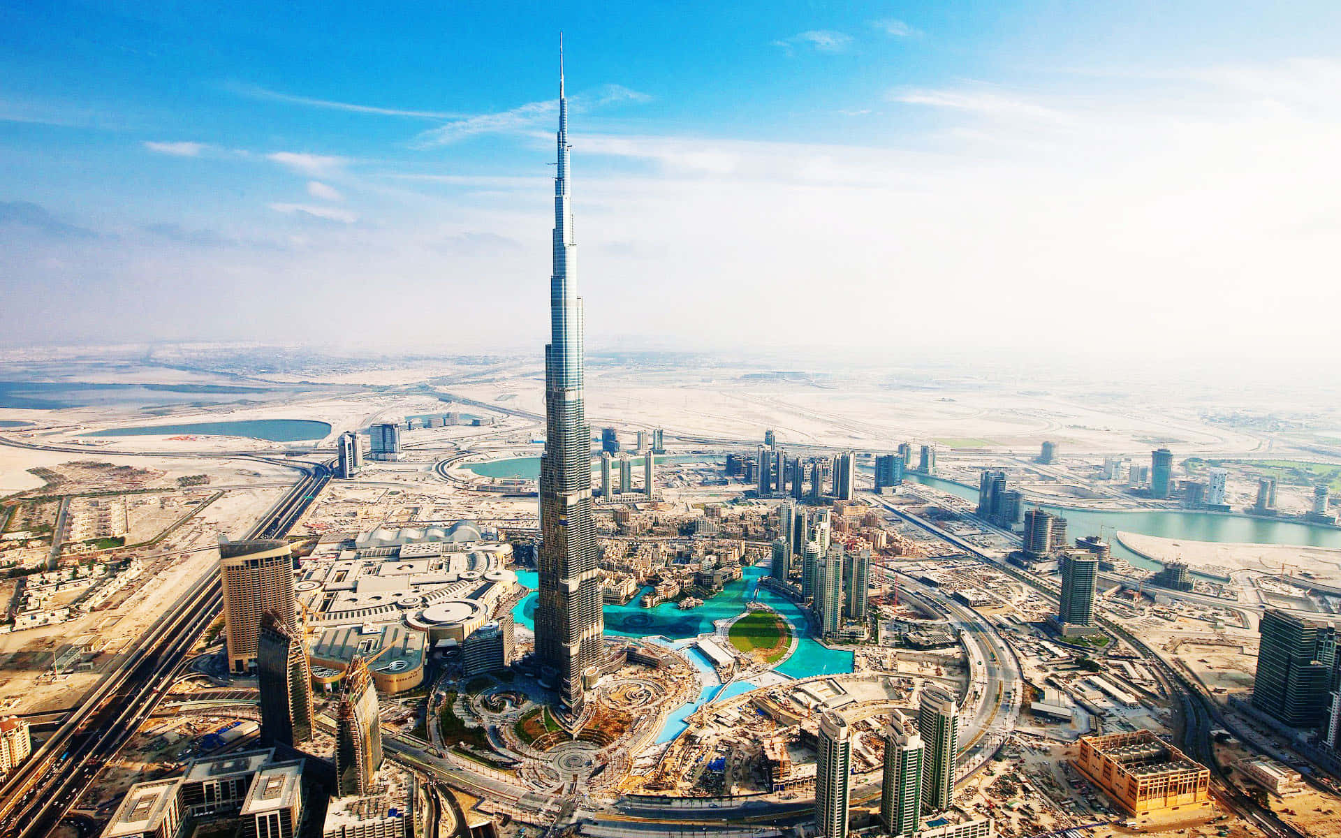 Burj Khalifa 桌布 壁紙 — 杜拜天際線的航拍圖，哈利法塔聳立於現代摩天大樓和沙漠景觀之上，天空湛藍明亮。