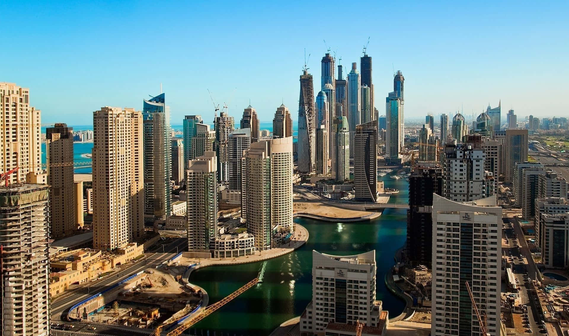 Dubai 桌布 壁紙 — 杜拜未來主義天際線的鳥瞰圖，高聳的摩天大樓在蜿蜒的水道上反射陽光。