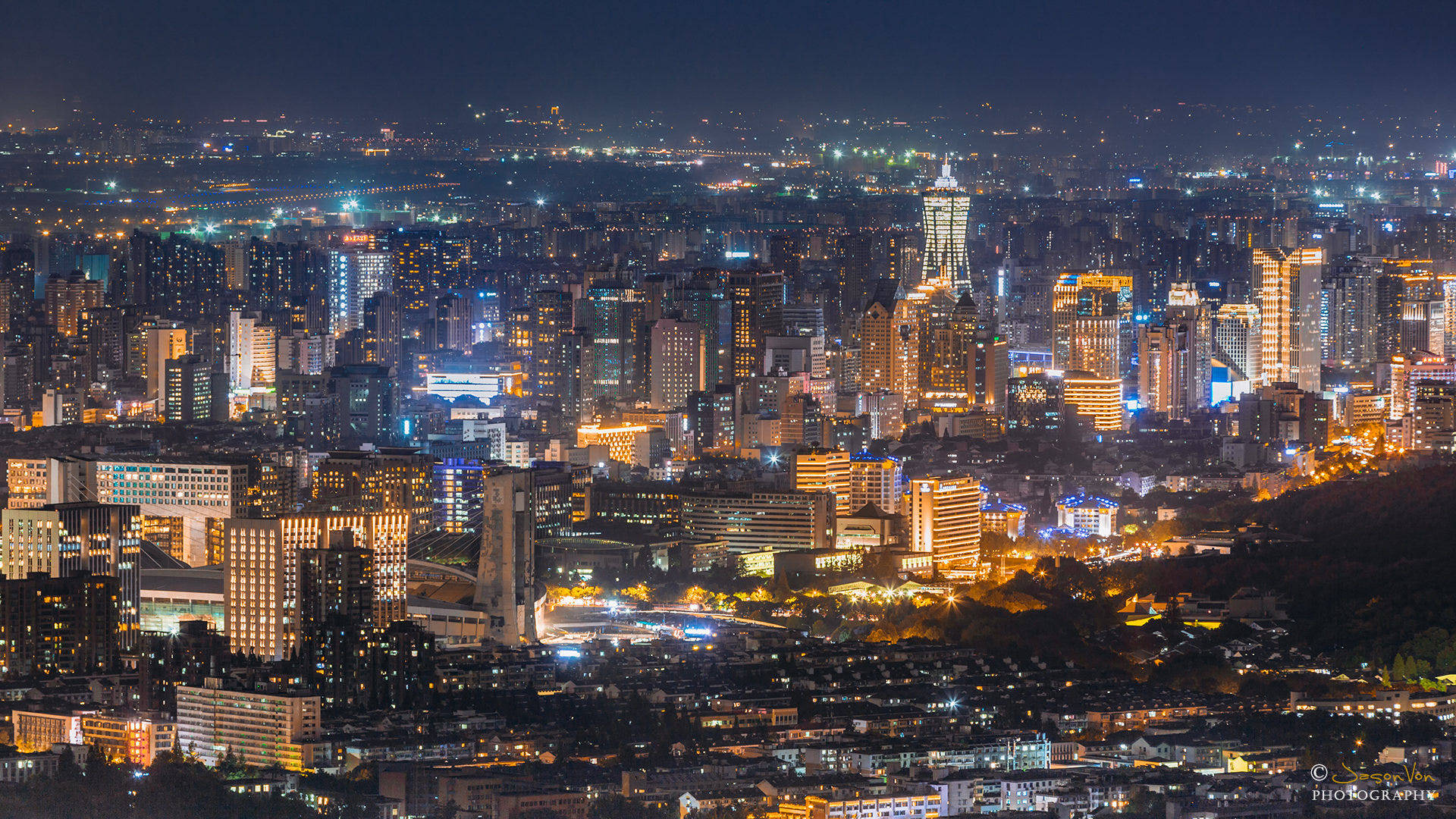 杭州城市夜景燈光 壁紙 — 夜晚廣闊的城市景觀，無數發光的窗戶和燈火通明的摩天大樓延伸至遠方。
