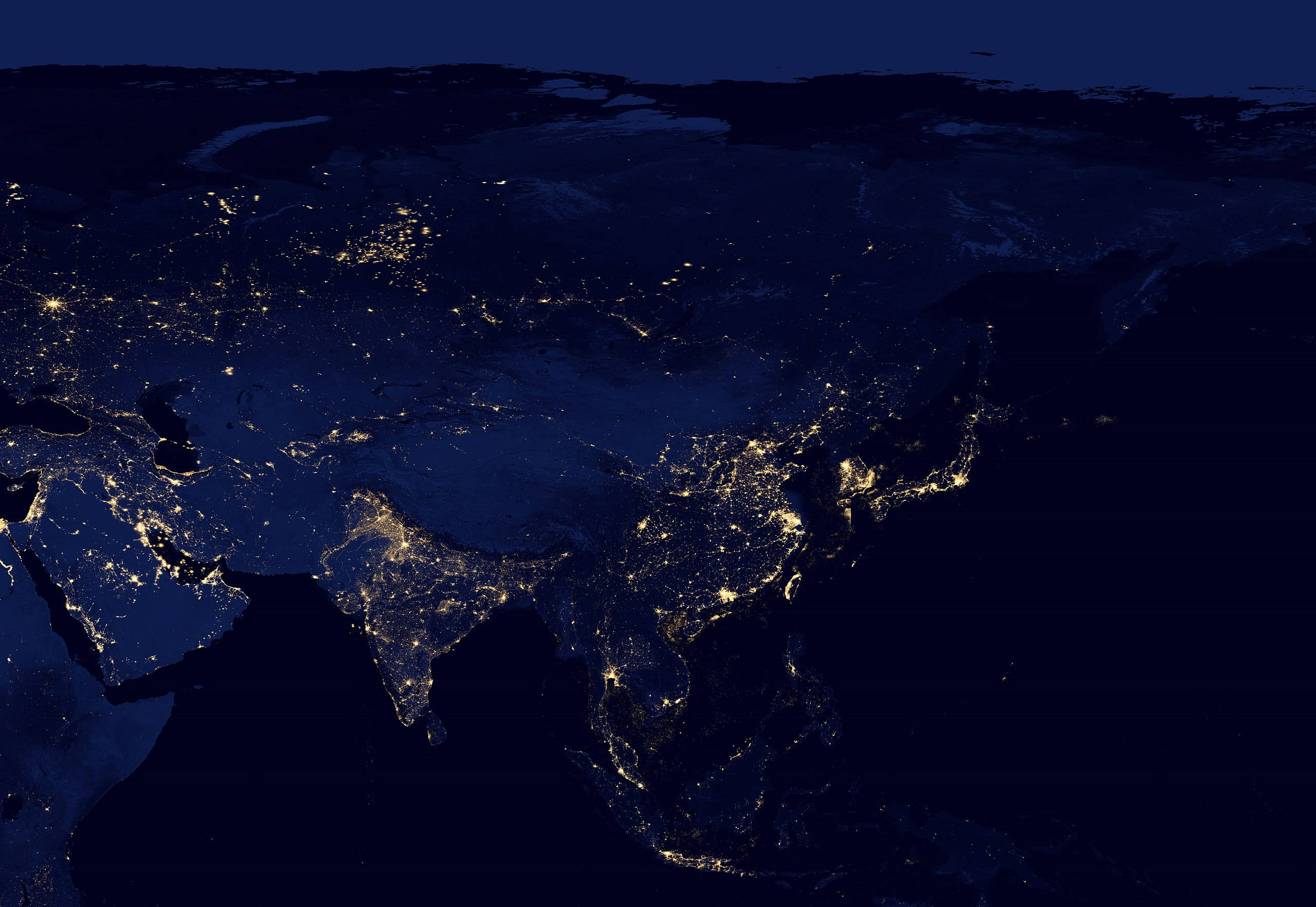 東亞夜景 壁紙 — 從太空俯瞰地球的壯麗夜景，在深藍色背景下展現亞洲和歐洲閃爍的城市燈光。