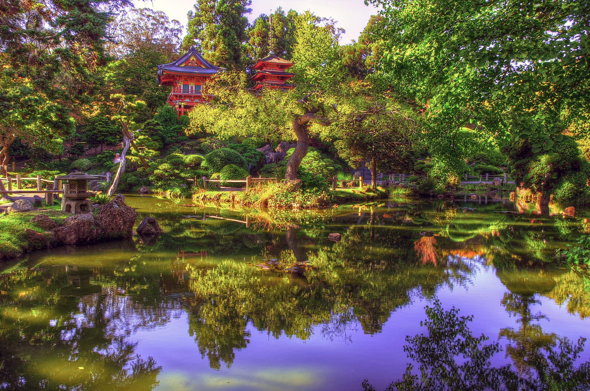 一個寧靜的日本花園，池塘倒映著紅色寶塔和茂密的綠樹。