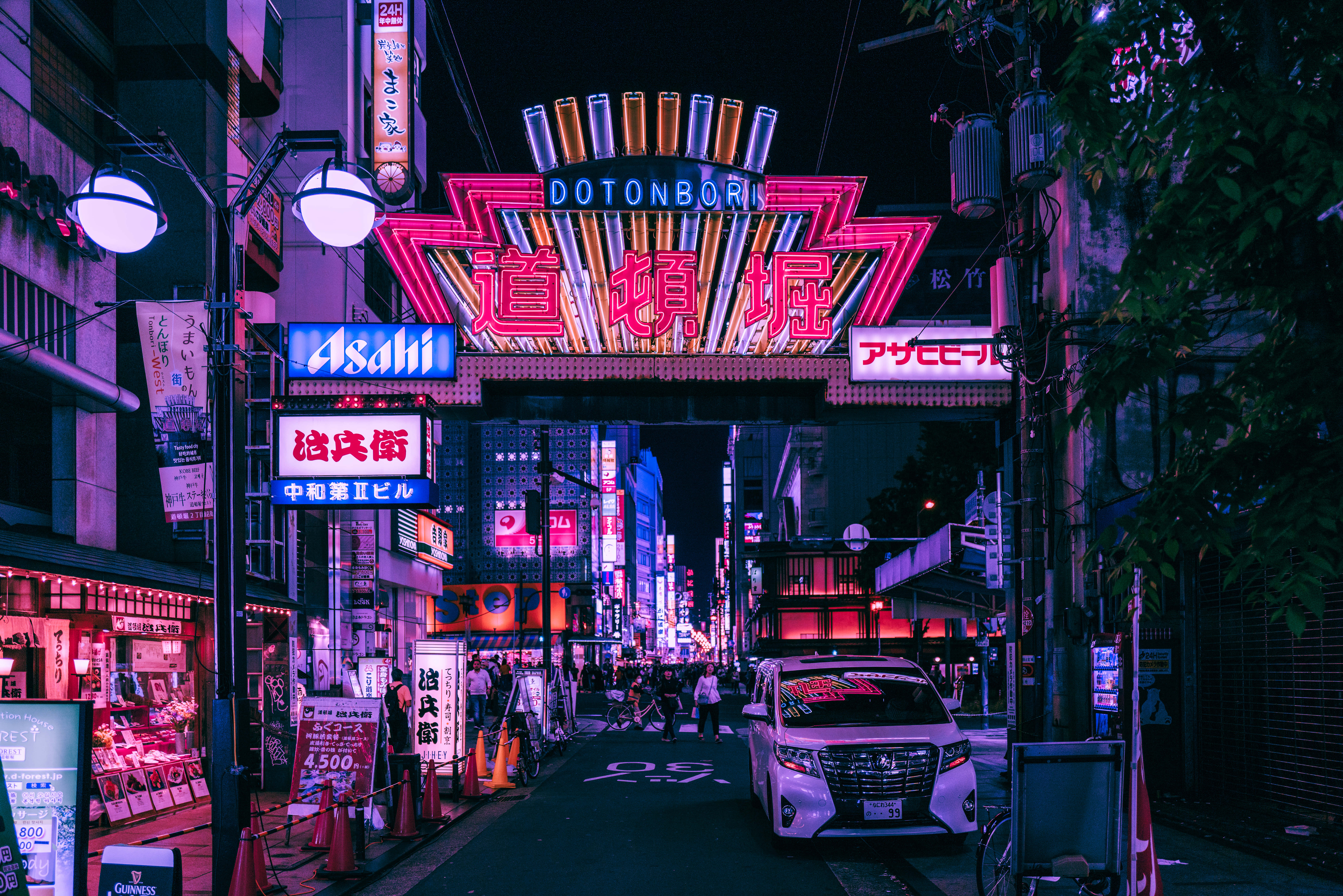 東京城市在日式霓虹燈下熠熠生輝 壁紙 — 充滿活力的霓虹燈招牌照亮了夜晚繁忙的東京街道，粉紅色、紫色和藍色的燈光在潮濕的人行道上反射。