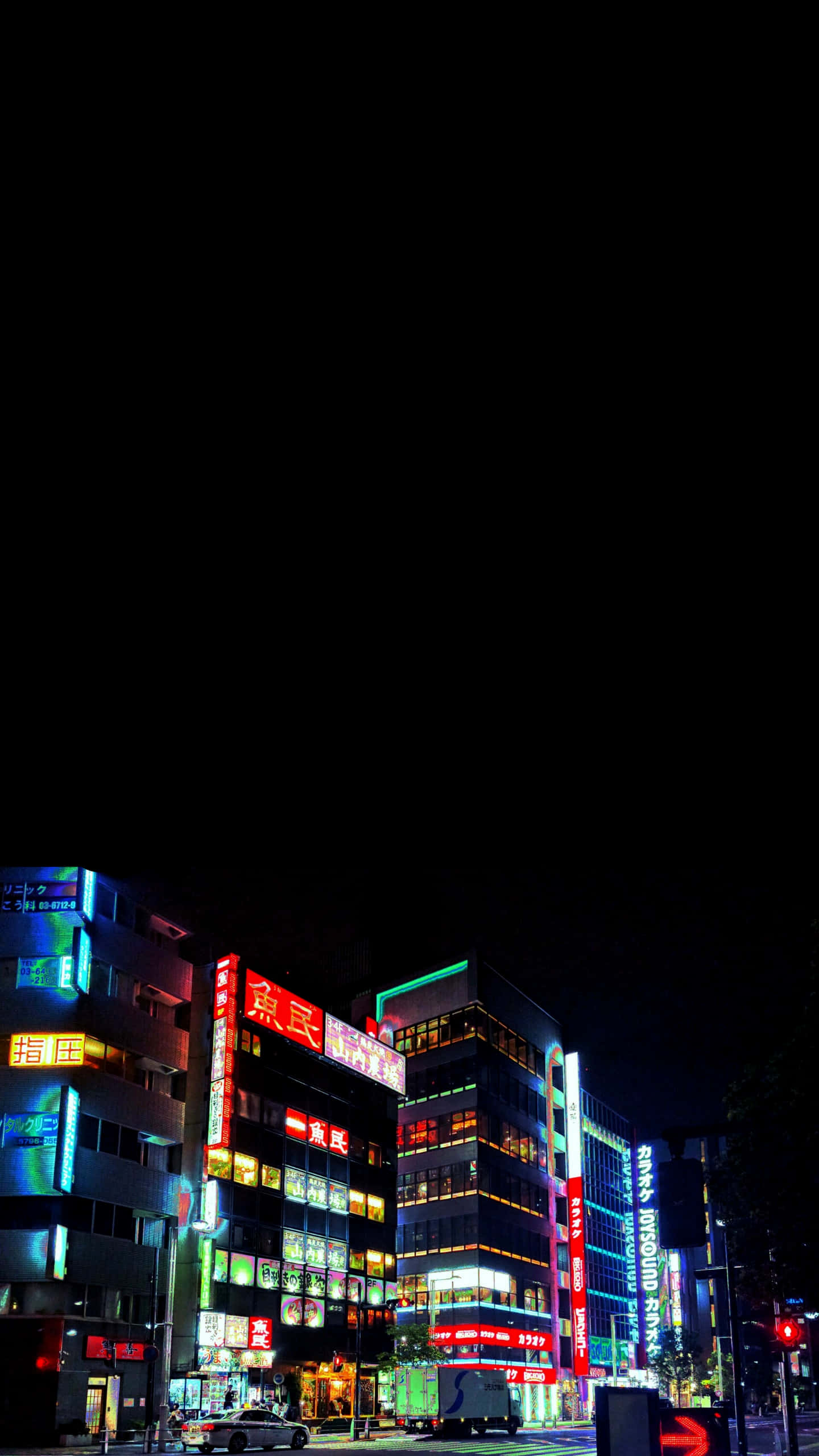 東京夜景 OLED 高畫質背景 壁紙 — 鮮豔的霓虹燈照亮了夜晚繁忙的日本城市街道，背景是漆黑的天空。