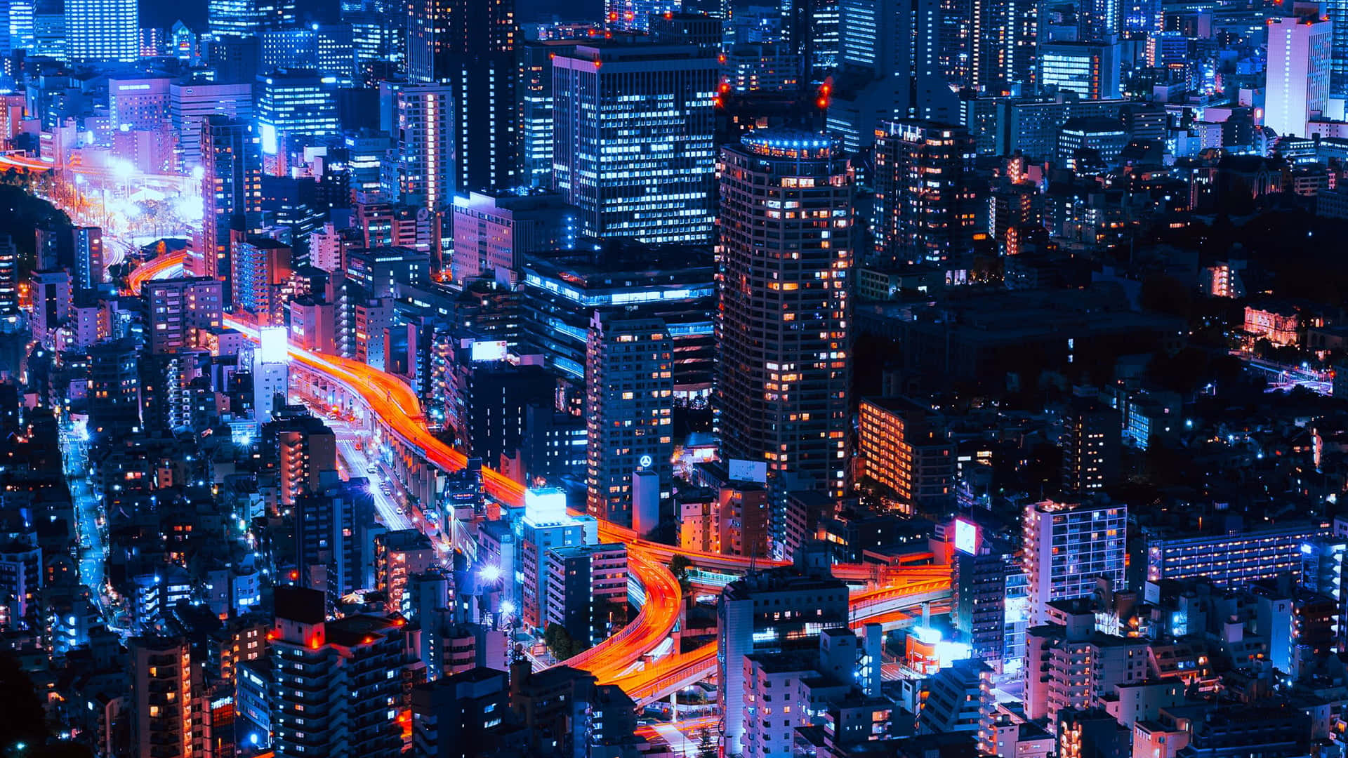 東京夜景城市 壁紙 — 從空中俯瞰夜晚霓虹燈照亮的天際線，閃爍的摩天大樓和交通留下的鮮豔橙色光軌。