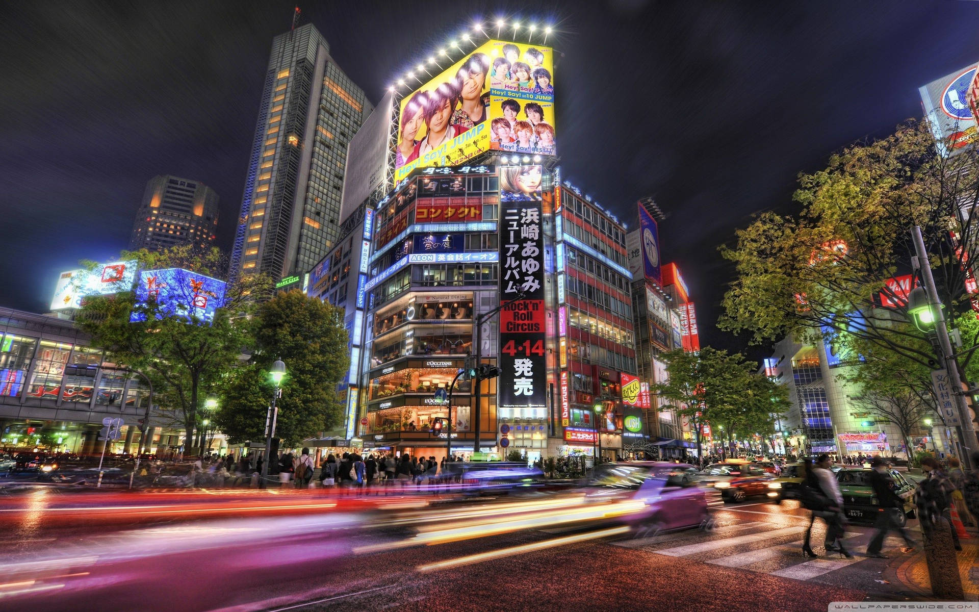 夜晚的東京城市街道，明亮的霓虹招牌和模糊的車輛燈光。