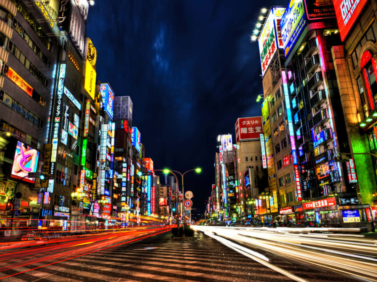 夜晚繁忙的霓虹城市街道，移動車輛留下的光軌。