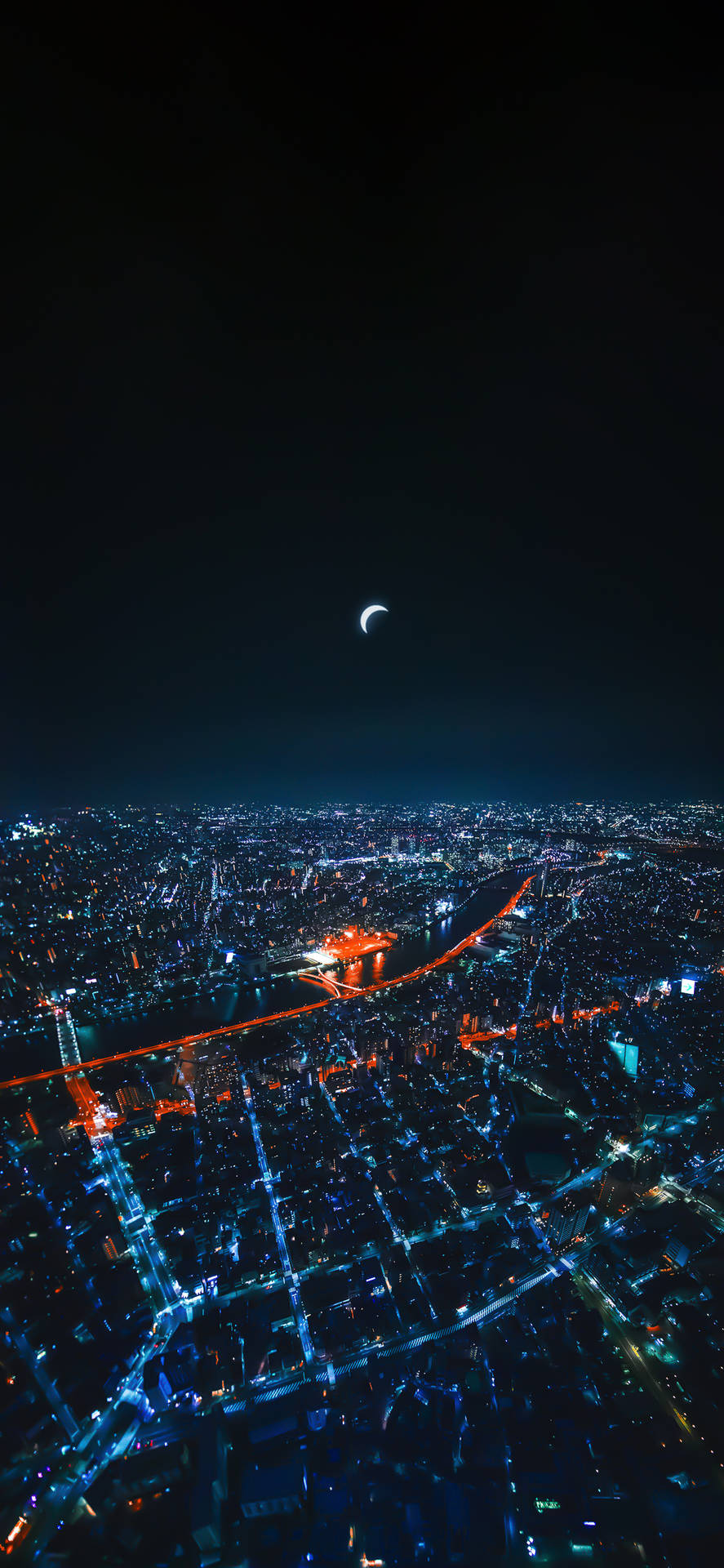 東京天空樹夜景空中俯瞰 壁紙 — 新月下，藍色和橙色燈光照亮的廣闊城市景觀的空中夜景。