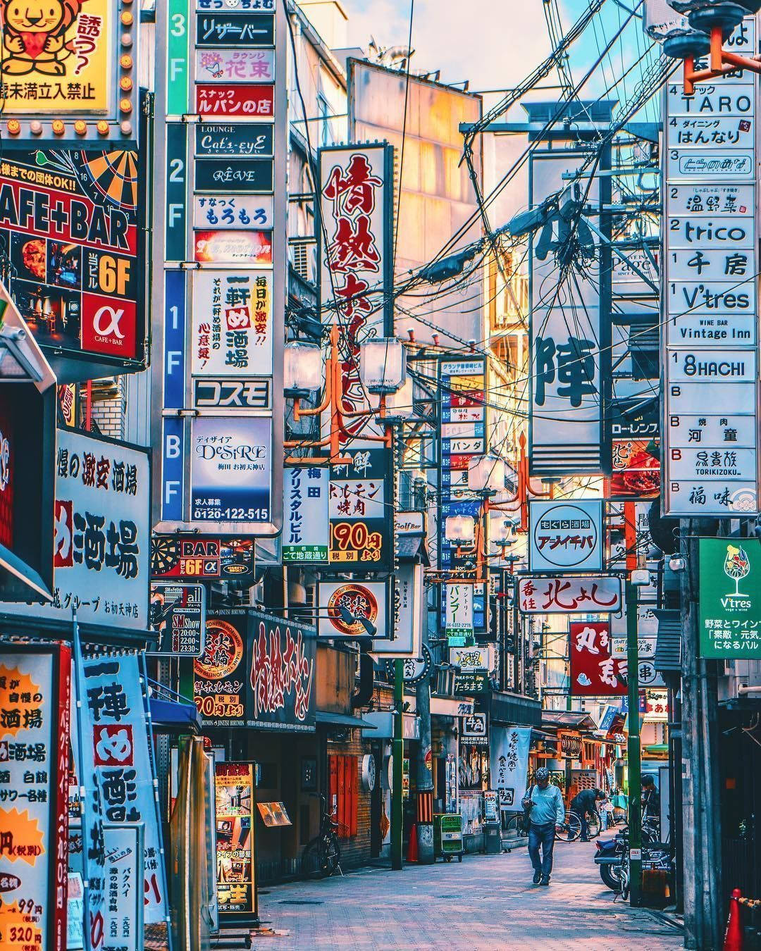 日落時分繁忙的東京小巷，閃爍著霓虹燈招牌和架空電線。