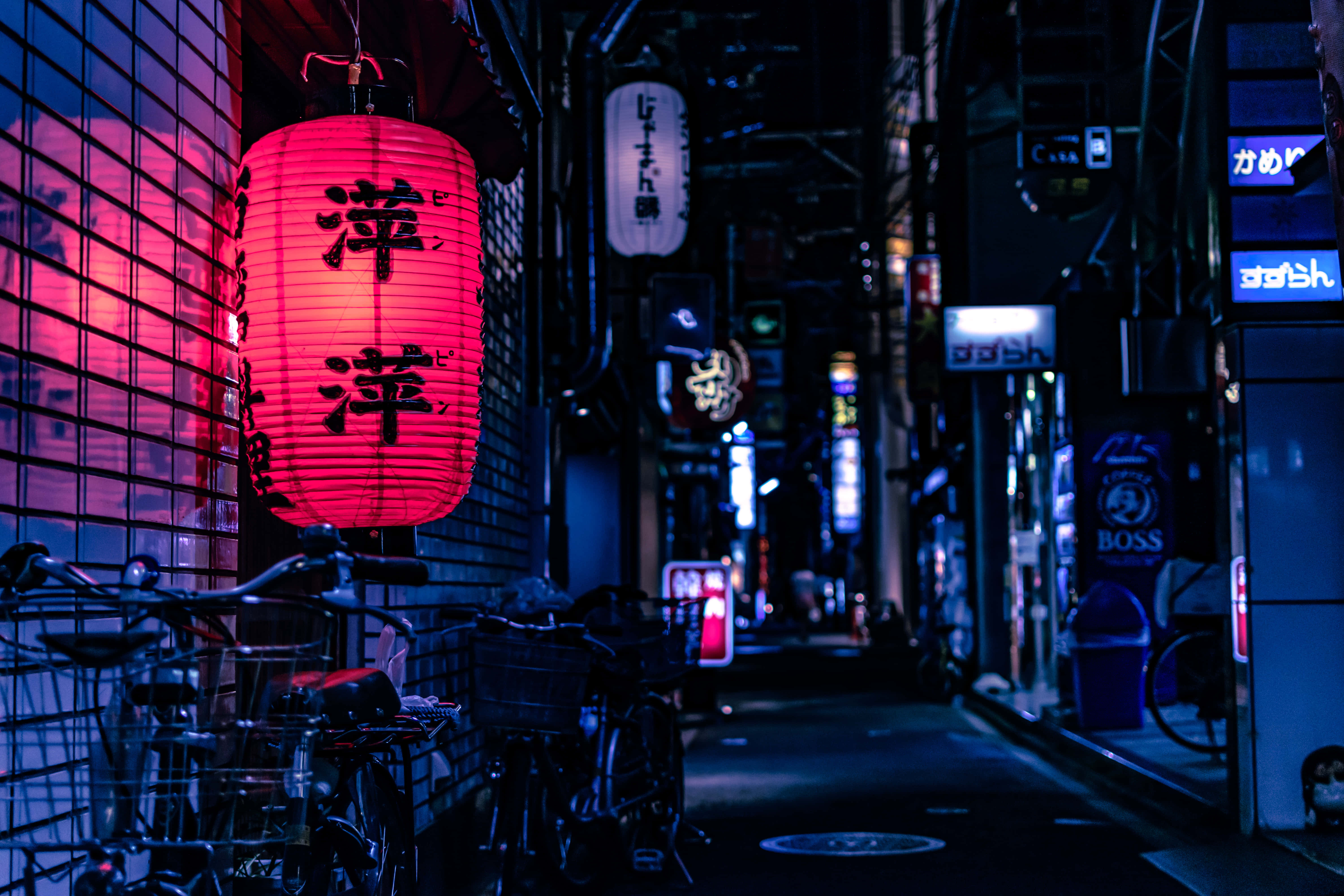 東京日本傳統霓虹招牌 壁紙 — 一個發光的紅色燈籠，上面有日文字，掛在一條狹窄的霓虹燈小巷裡，夜晚有停放的單車。