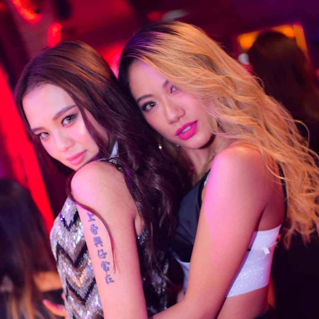 兩位女士在紅色燈光下的夜總會一起擺姿勢。
