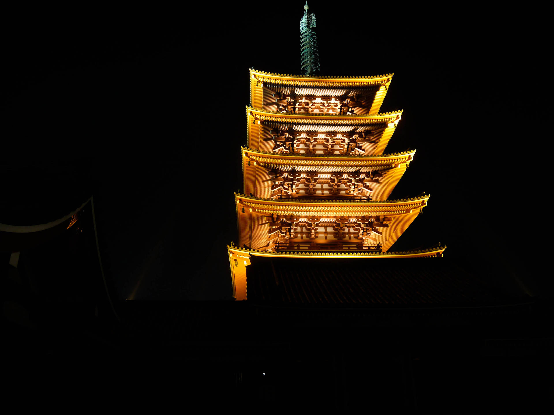 一座發光的日本寶塔在黑暗的夜空中高高聳立。