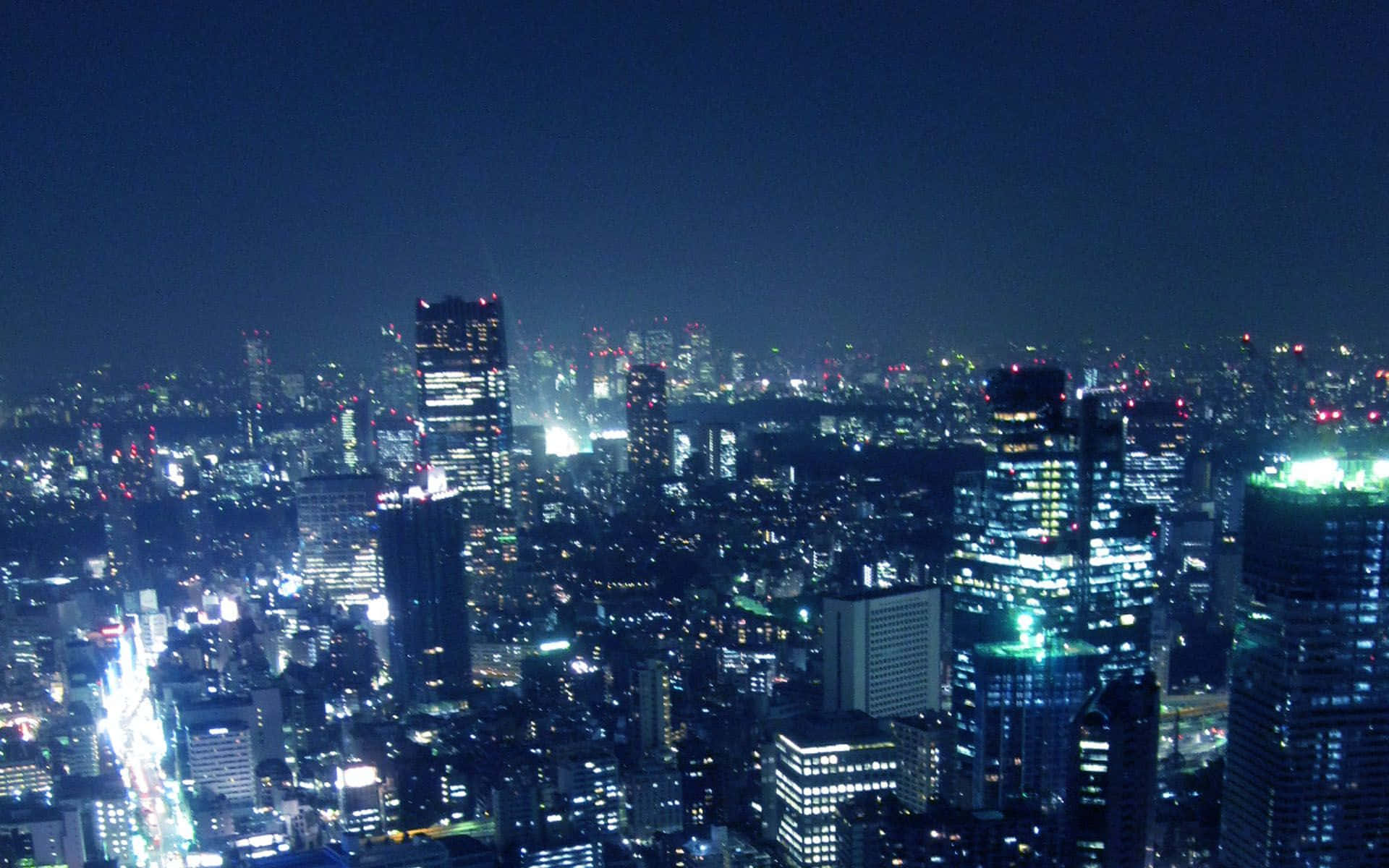 東京燈光璀璨的城市背景 壁紙 — 廣闊的城市夜景，無數燈火通明的摩天大樓和發光的街道在黑暗的天空下。
