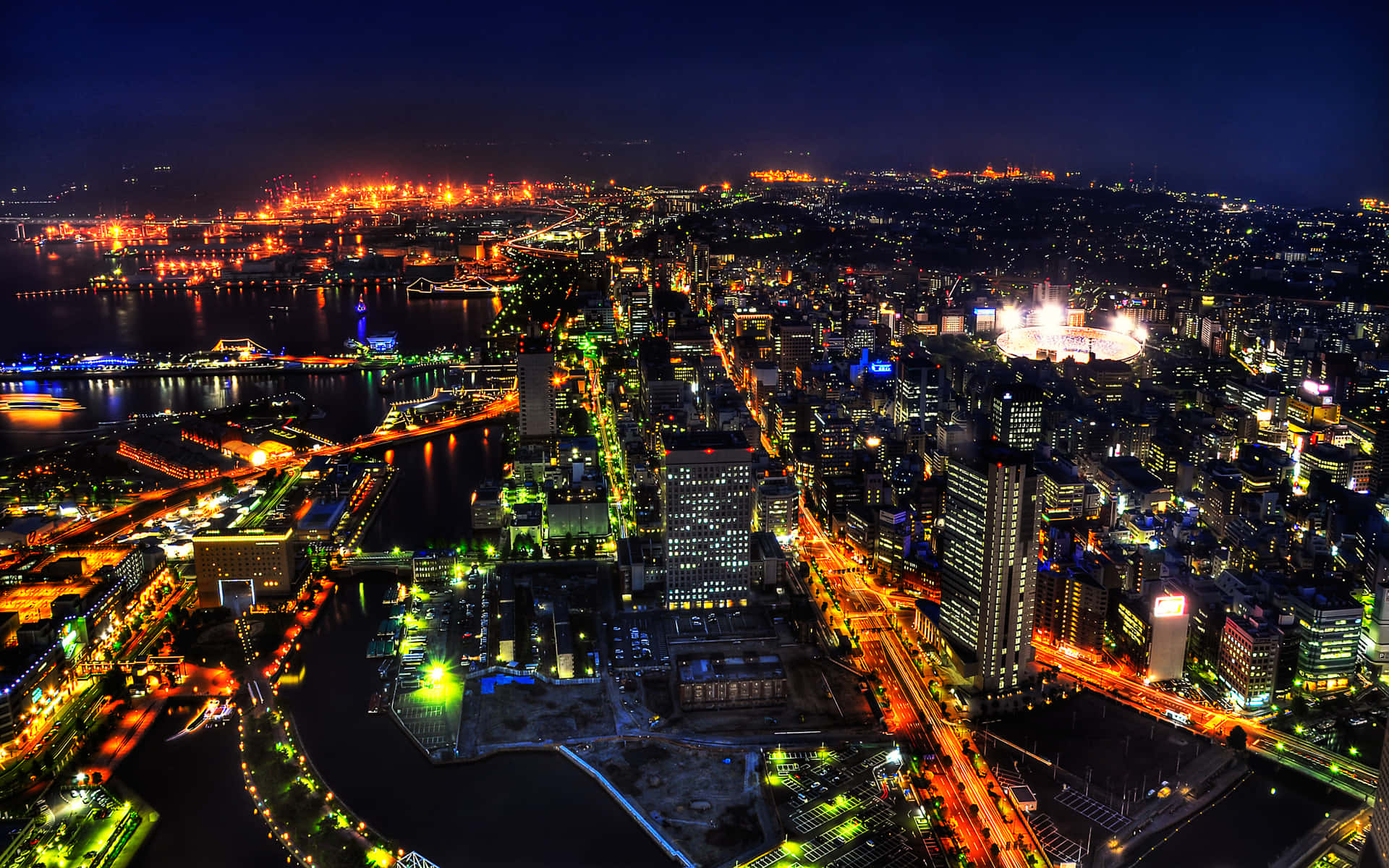閃爍的城市夜間鳥瞰圖，河畔橋樑和燈火通明的街道。