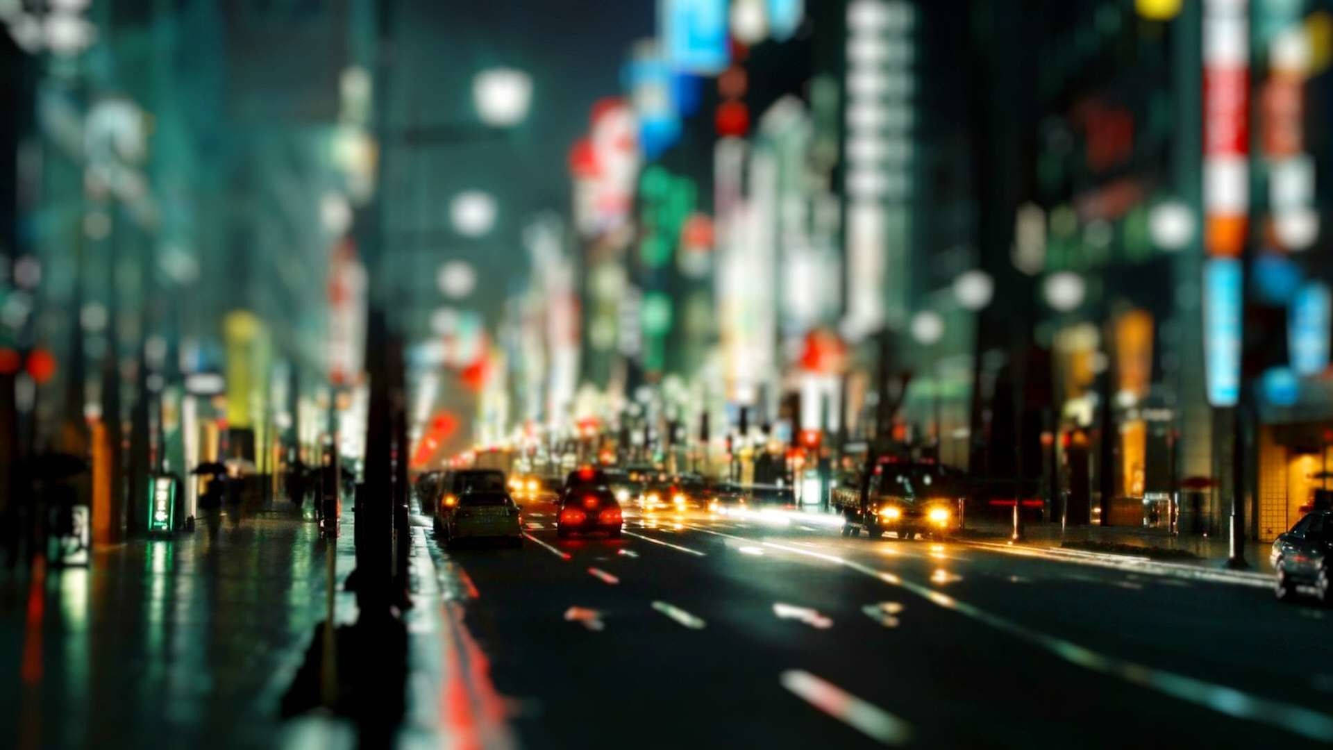 夜間城市街道，帶有模糊的霓虹燈和移動的汽車。