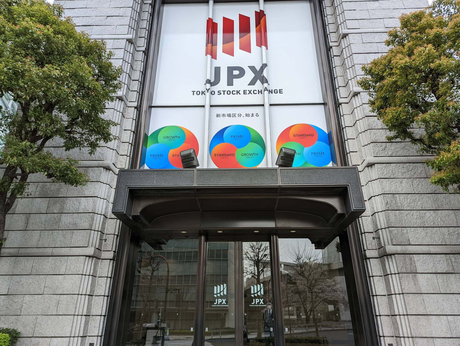 東京證券交易所大樓入口，帶有市場細分標誌和樹木
