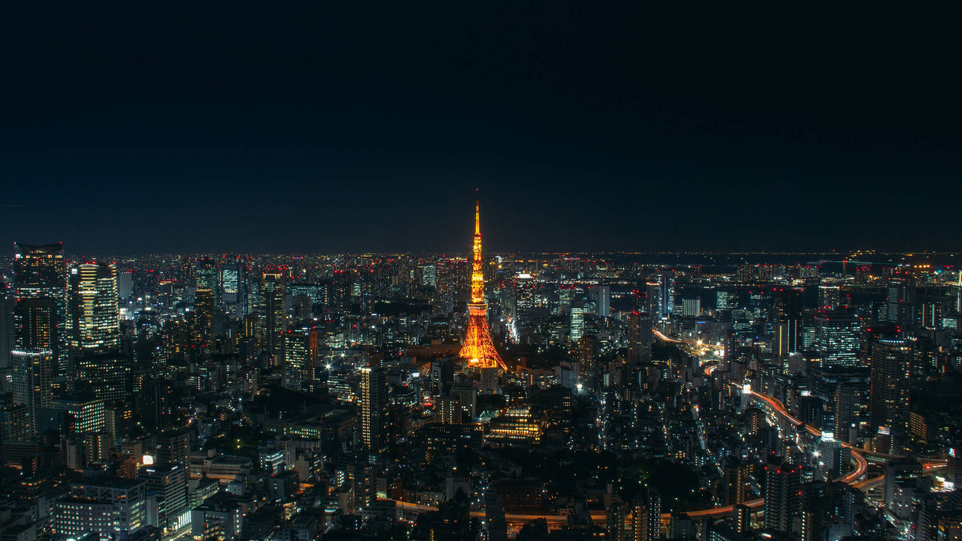 東京鐵塔夜景燈光 壁紙 — 夜晚的東京天際線，明亮的東京塔在閃爍的摩天大樓和蜿蜒的道路中高聳入雲。