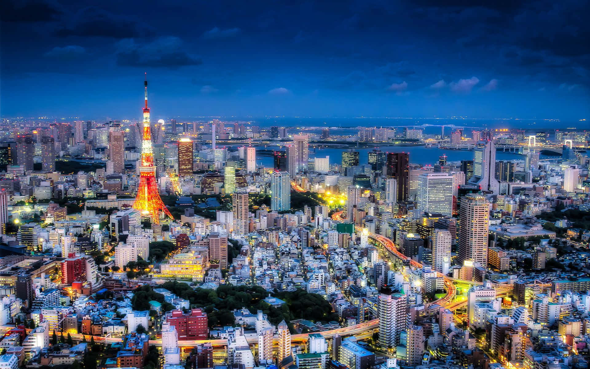 黃昏時分的東京城市景觀，燈火通明的建築物和東京塔在深藍色天空下閃耀。