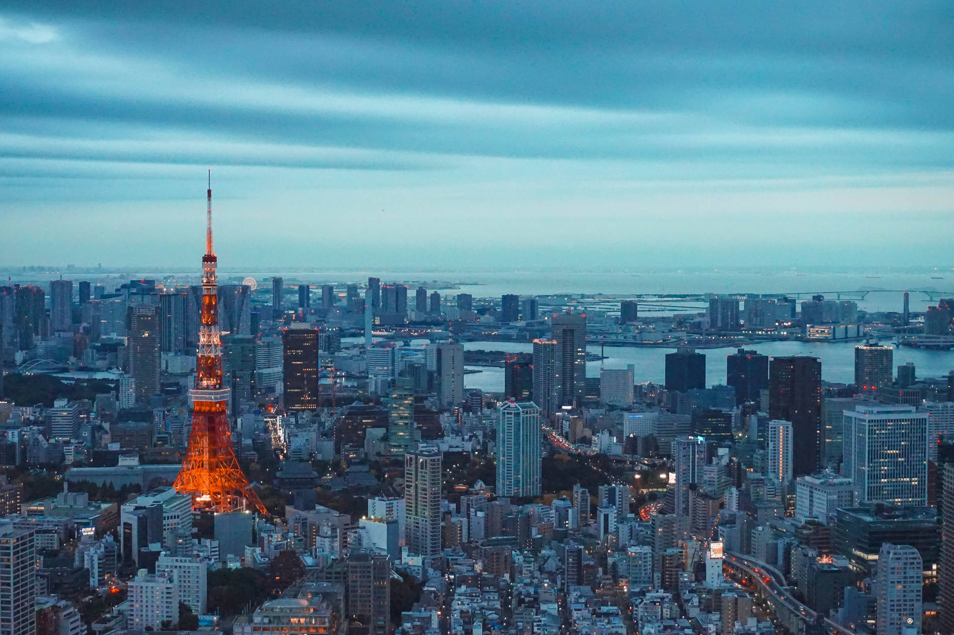 東京鐵塔紅光映藍白天際 壁紙 — 東京塔在暮色藍天下溫暖發光，城市燈光在都市擴展區中閃爍。