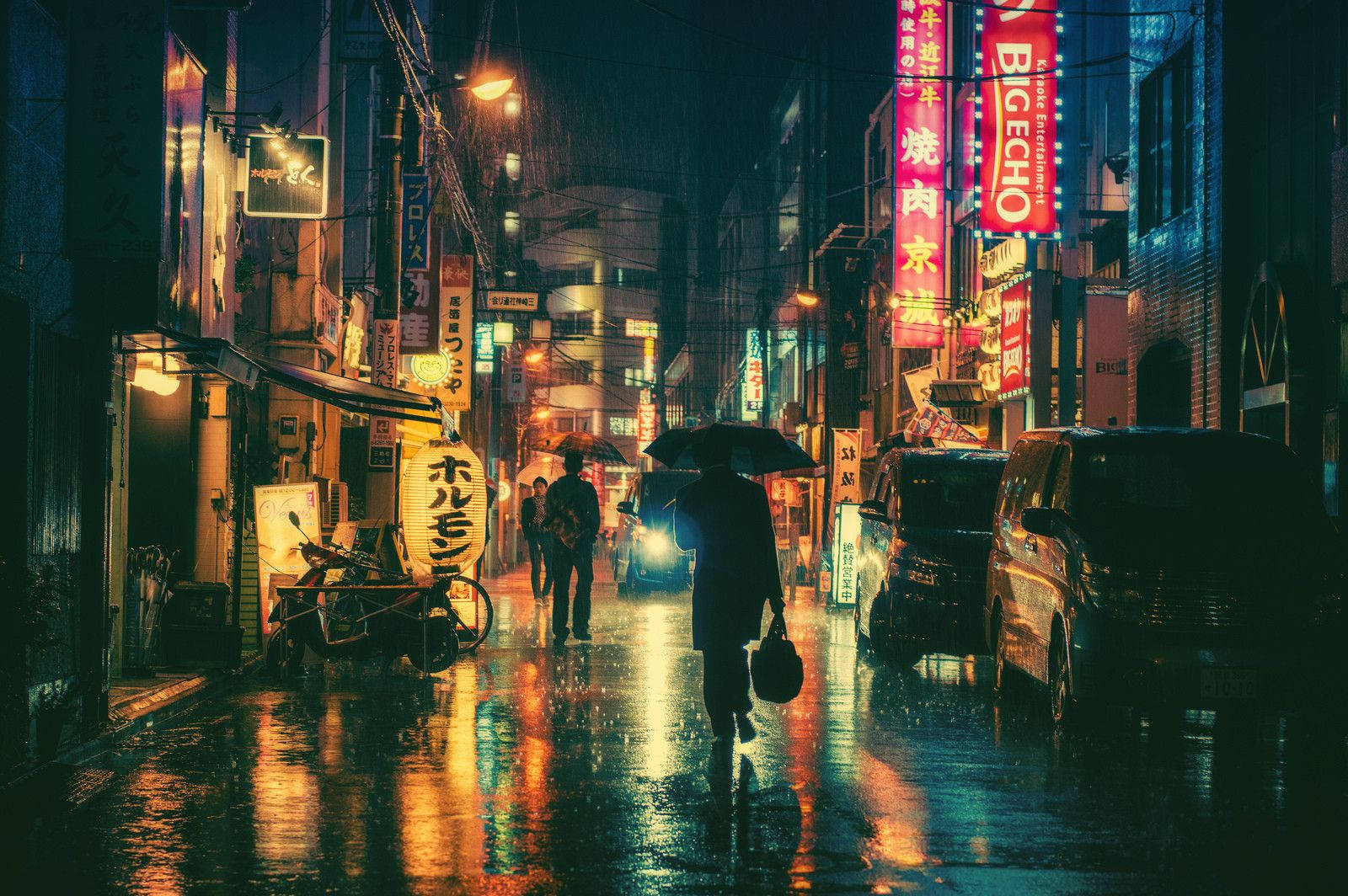 夜晚在潮濕的霓虹燈日本城市街道上撐傘行走的人。