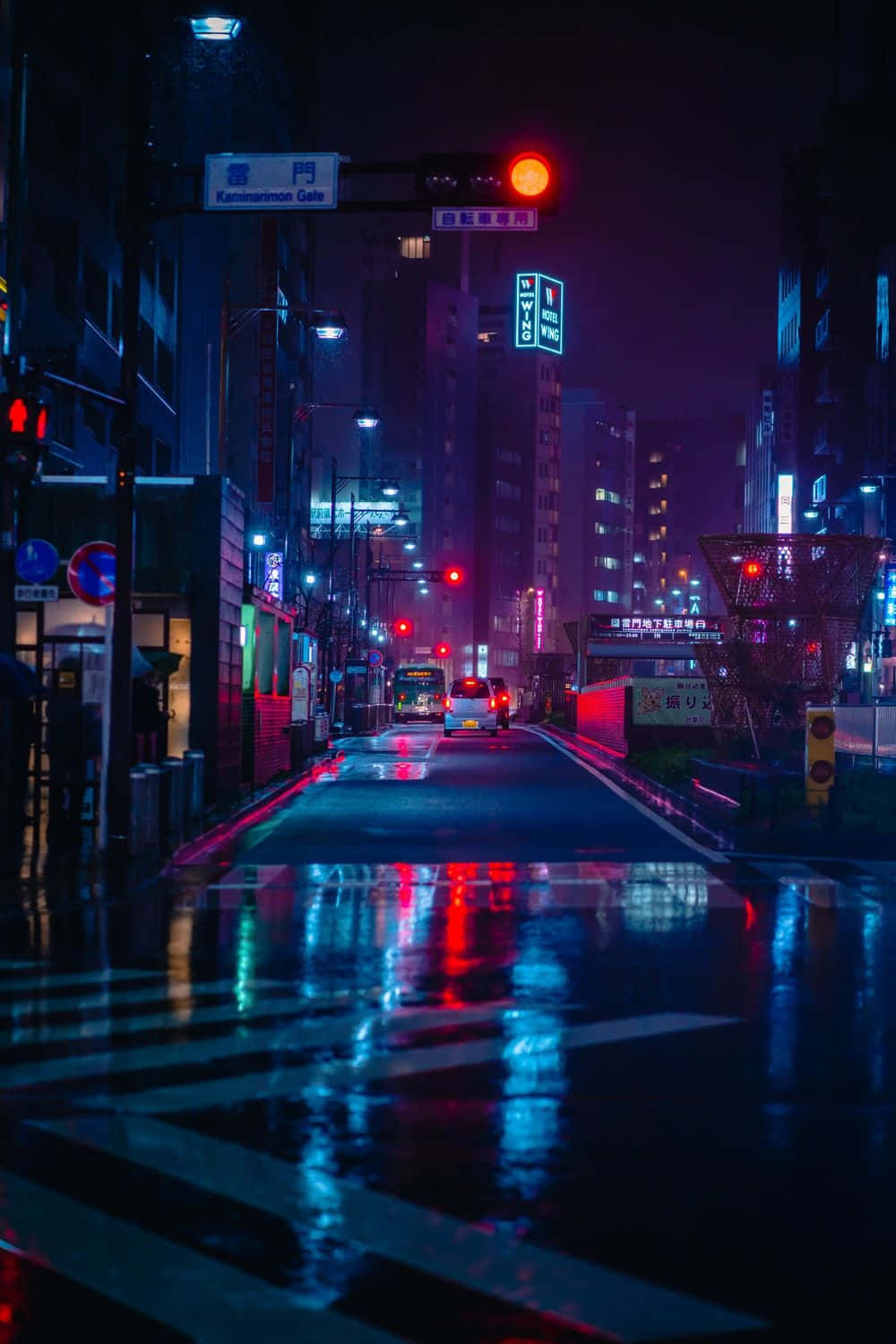 雨濕的東京街道在夜晚閃爍著霓虹反射和紅色交通燈。