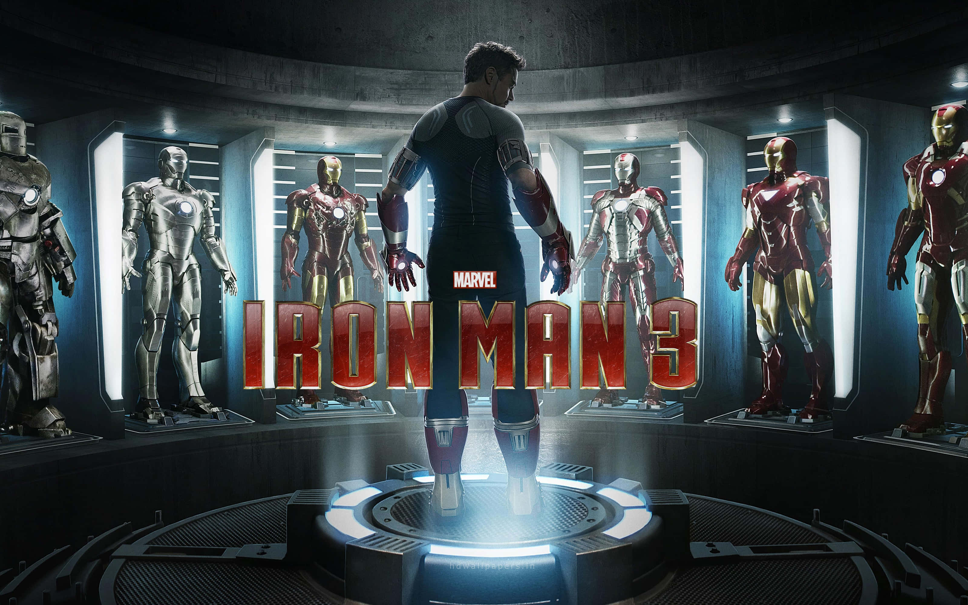 Superhero Movies 桌布 壁紙 — 東尼·史塔克站在高科技實驗室中，周圍環繞著發光的鐵甲奇俠戰衣，電影標題顯眼地展示。