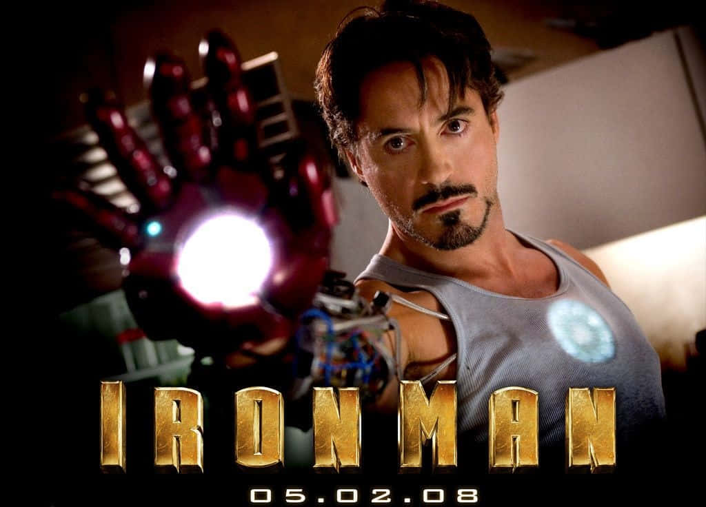 Iron Man Movies 桌布 壁紙 — 東尼·史達克身穿灰色背心，在昏暗的實驗室中舉起發光的紅色斥力手套，眼神專注。
