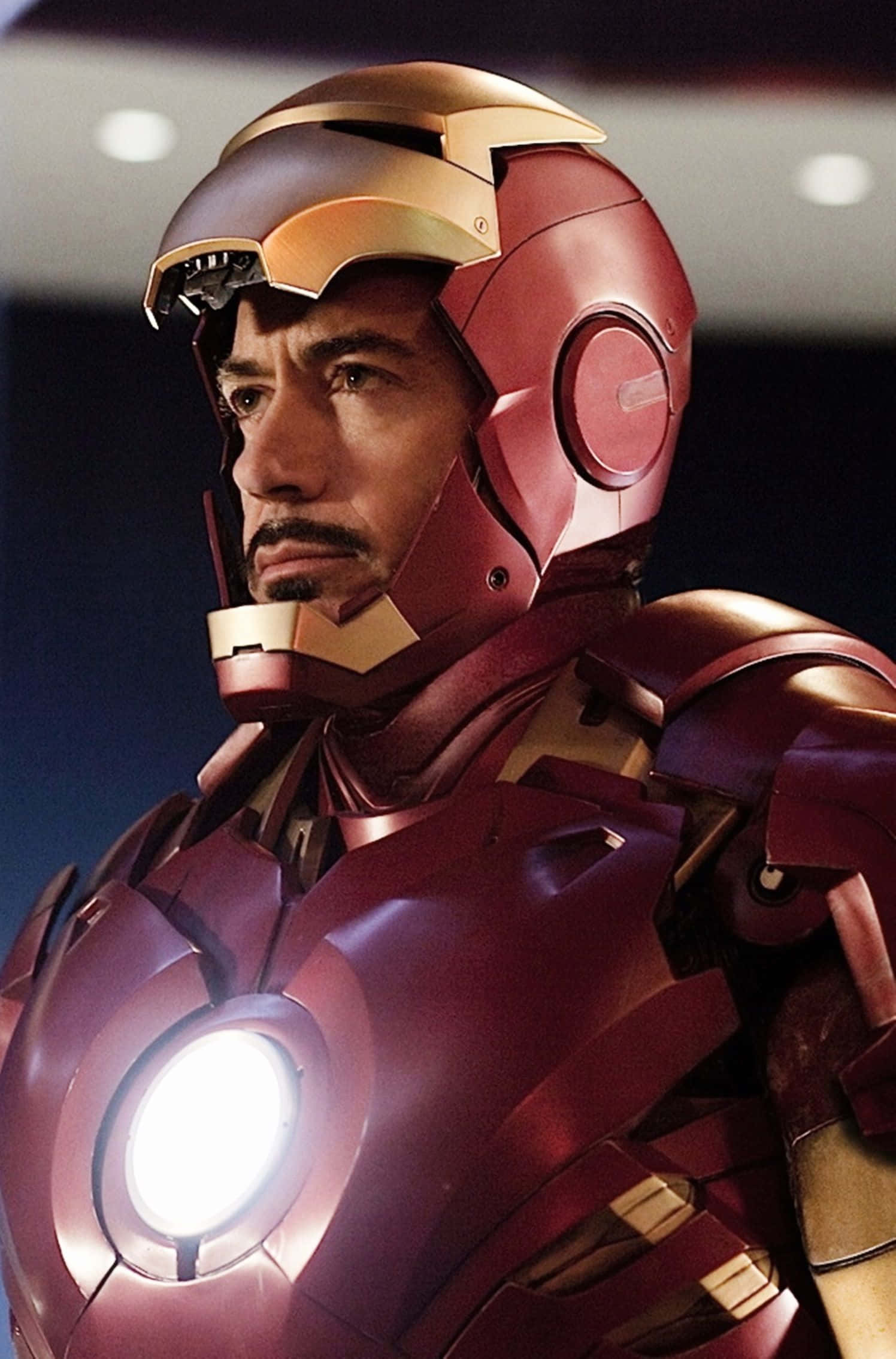 Superhero Movies 桌布 壁紙 — 東尼史達穿上標誌性紅金色鐵甲奇俠裝甲，發光弧形反應器的特寫。