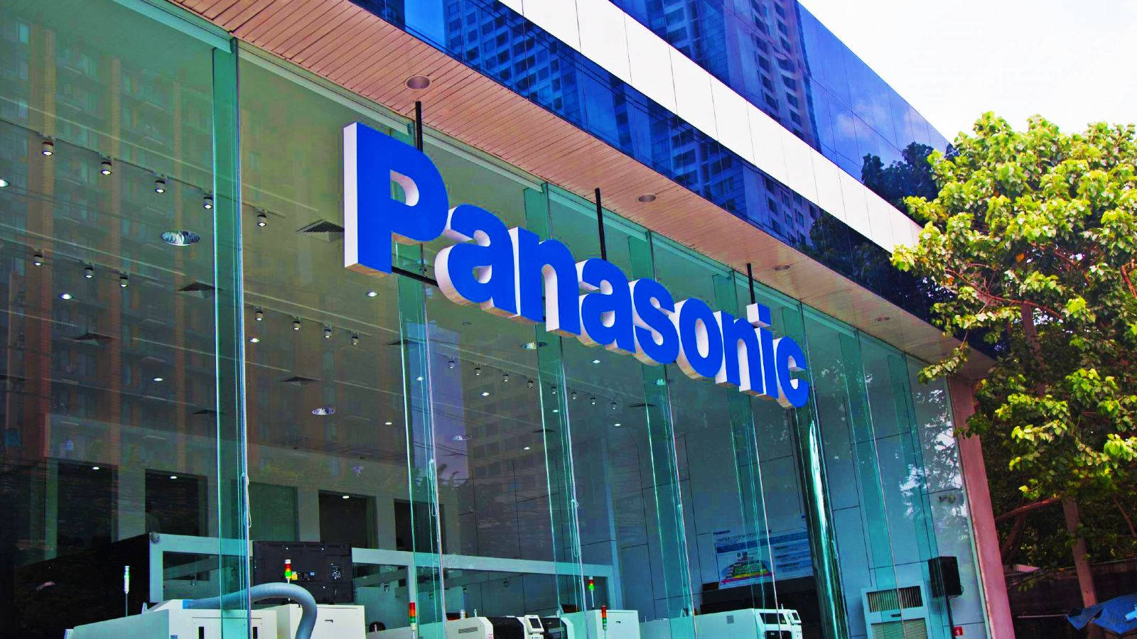 Panasonic企業大樓，玻璃外牆和藍色標誌，周圍環繞樹木。