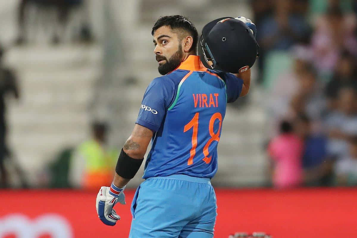 Virat Kohli 桌布 壁紙 — 板球運動員維拉·哥利身穿藍色18號球衣，將頭盔搭在肩上，回頭望向球場觀眾。