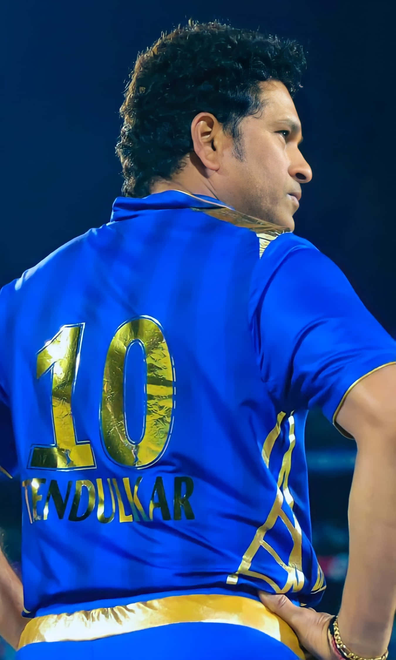 Sachin Tendulkar 桌布 壁紙 — 板球運動員薩欽·坦杜卡近照，身穿藍金色球衣，背後號碼10，雙手叉腰站在球場燈光下。