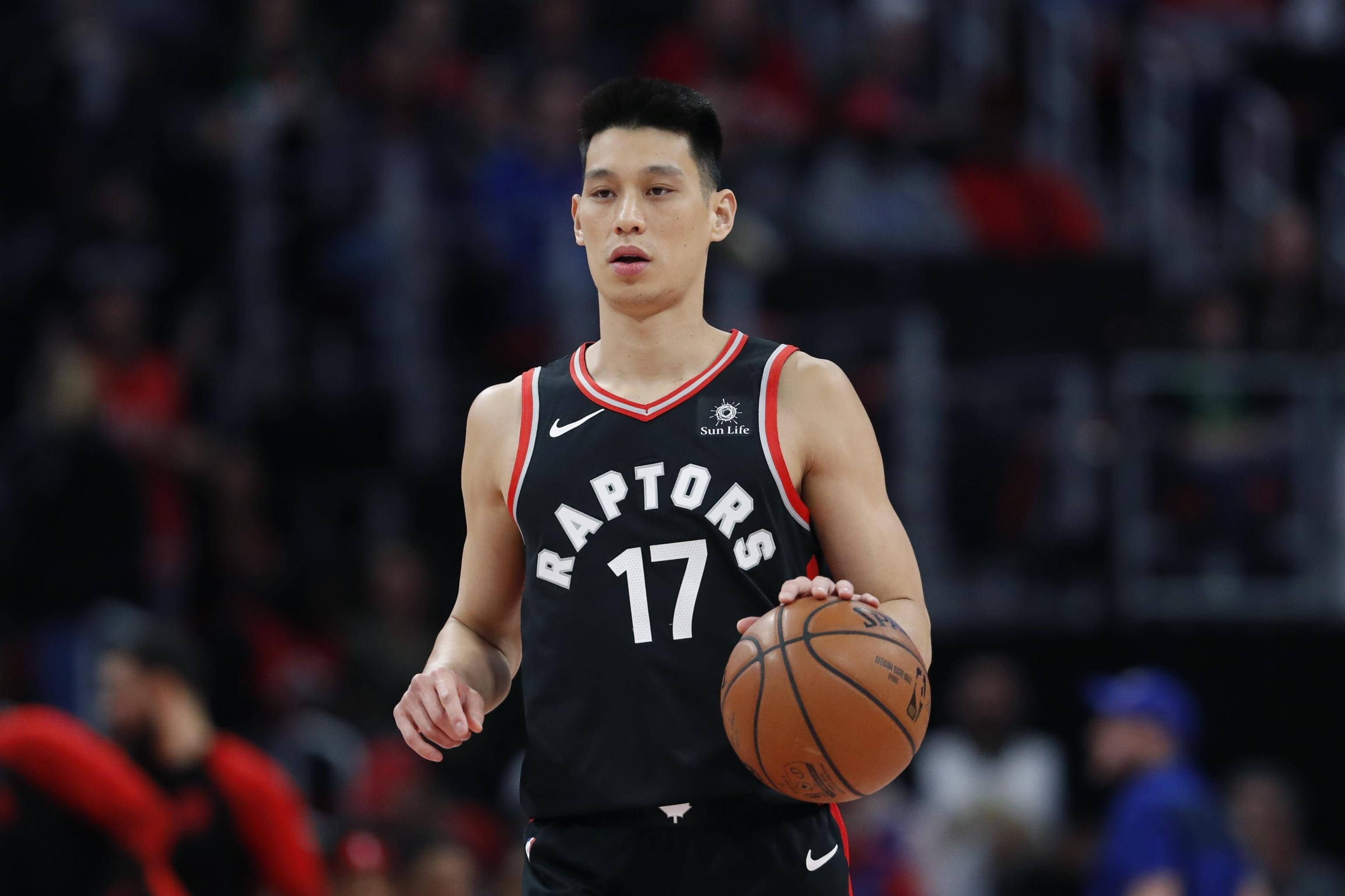 林書豪多倫多暴龍控衛 壁紙 — 一位專注的籃球運動員身穿黑色Raptors球衣，在場館燈光下比賽中持球。