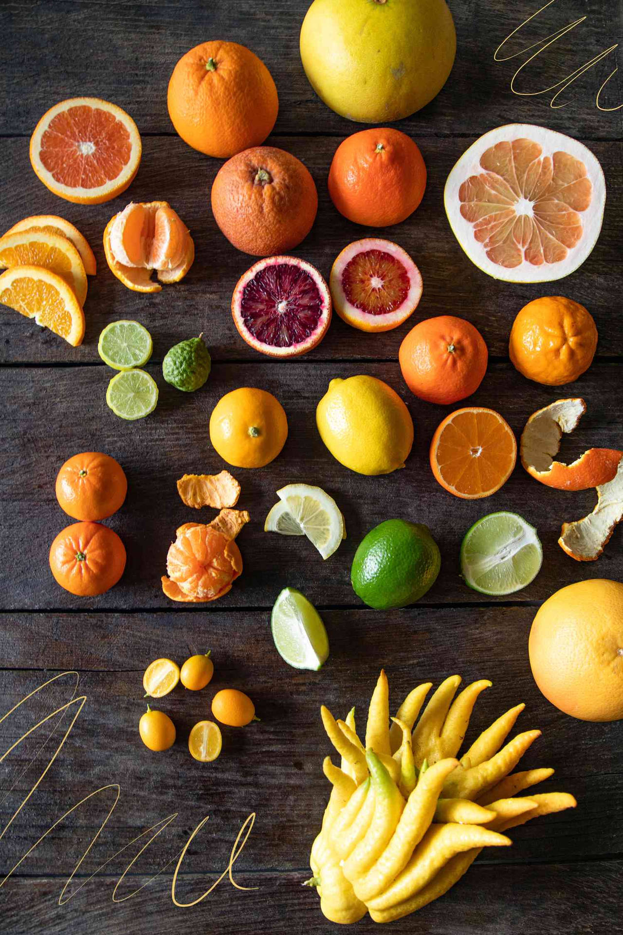 各種柑橘類水果，如橙、檸檬和青檸，排列在深色木頭上。