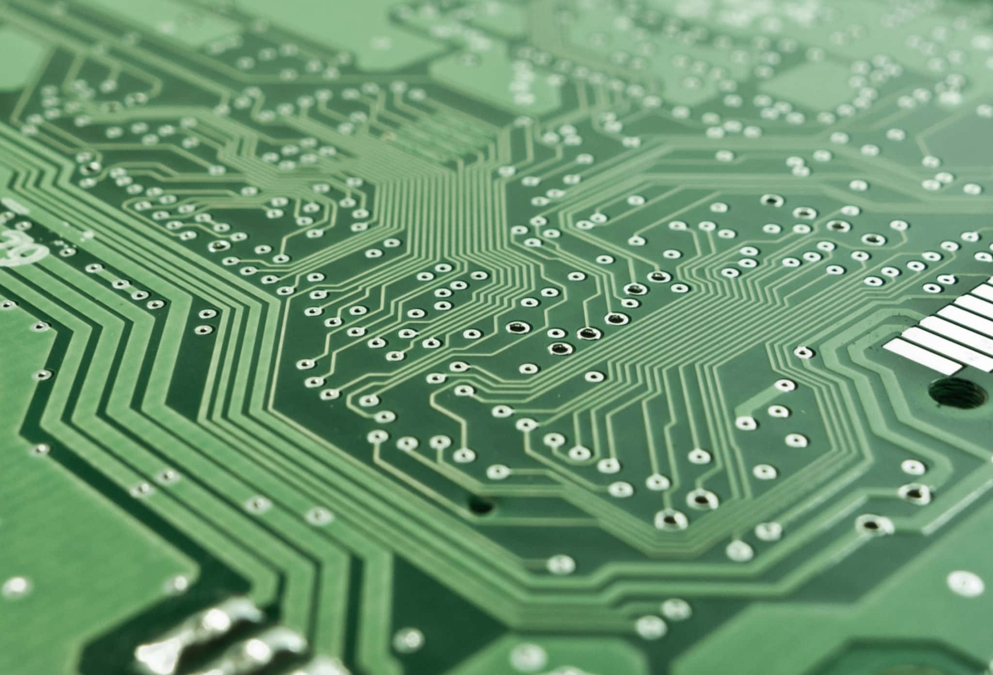 Electronics 桌布 壁紙 — 柔和燈光下綠色電路板的特寫，帶有複雜的銀色線路和焊點。