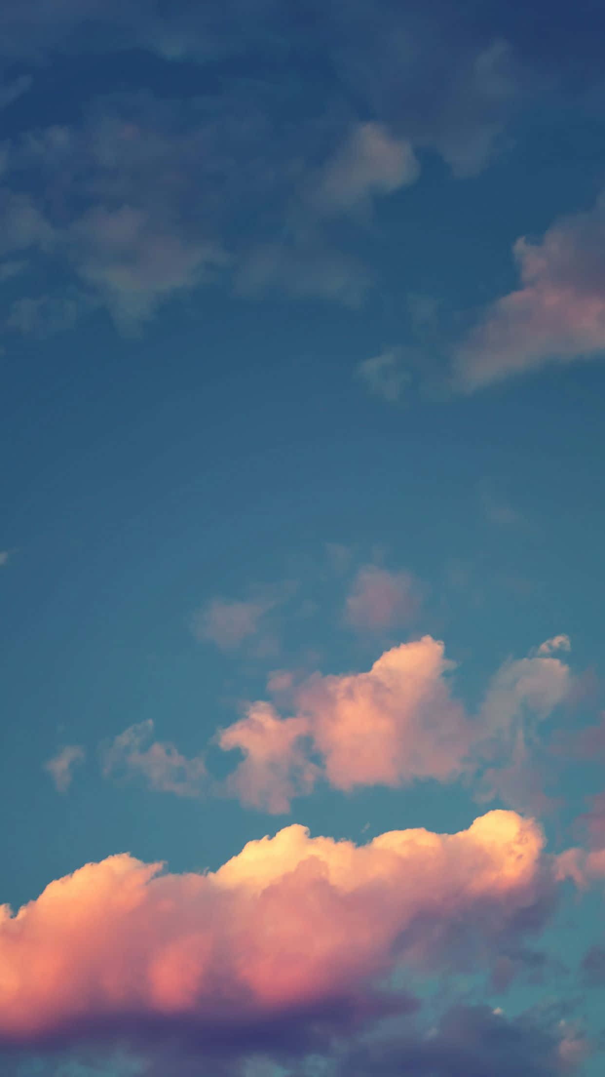 iPhone Home Screen 桌布 壁紙 — 柔和的粉紅色和橙色雲朵在深藍色的暮色天空中飄移，呈現寧靜的日落場景。