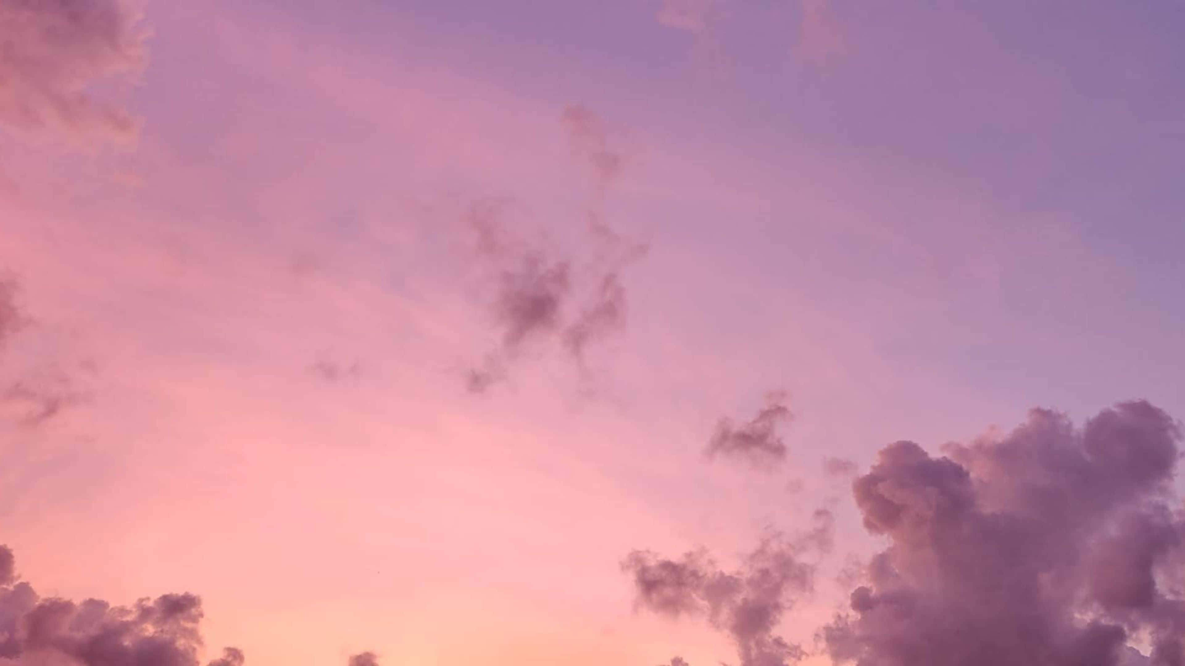唯美雲朵動態 桌布 壁紙 — 柔和的粉紅色和紫色雲彩在暮色天空中飄移，散發著溫暖的日落色調。