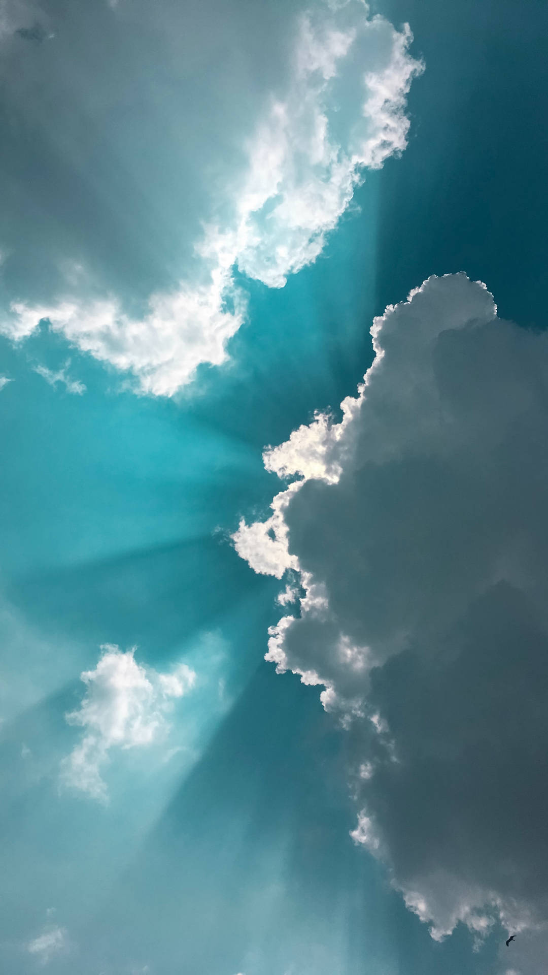 陽光穿過蓬鬆的白雲，在明亮的藍天中閃耀。