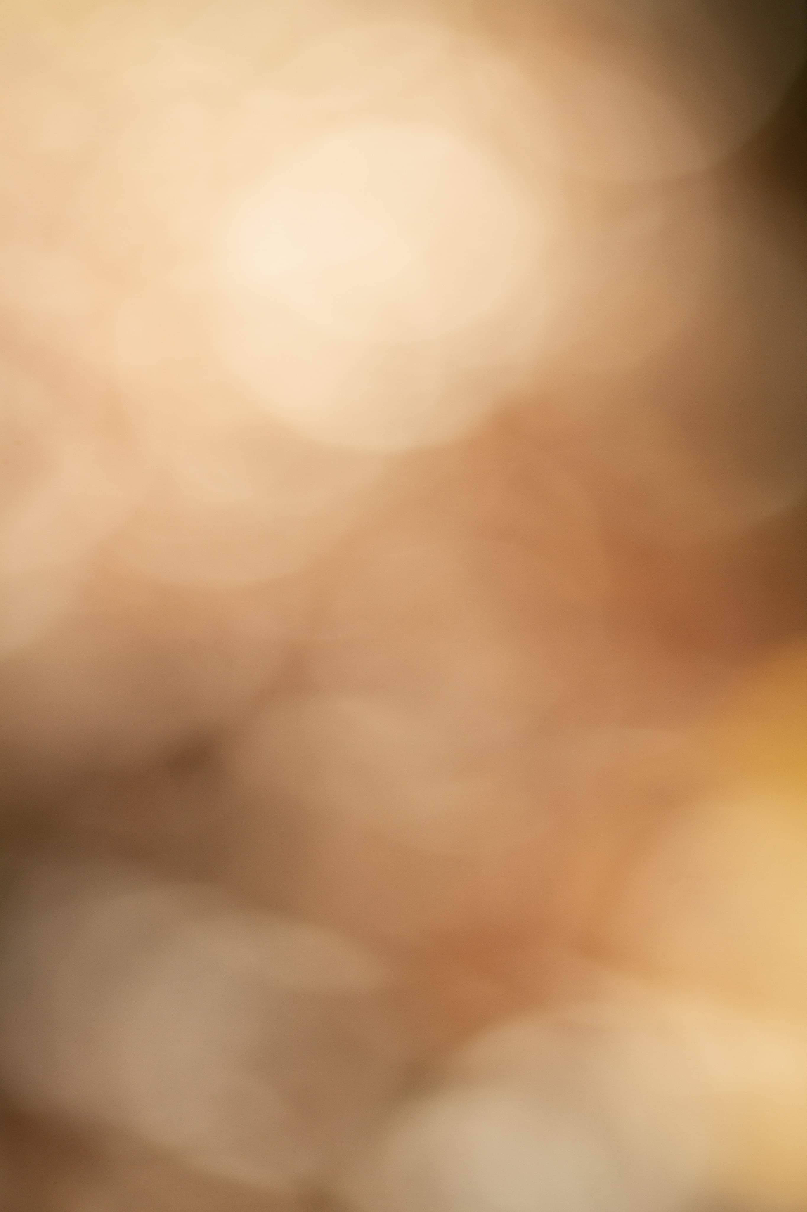 Beige Minimalist 桌布 壁紙 — 柔和的金色散景燈光模糊成溫暖的抽象光芒，帶有奶油色米色和琥珀色調。