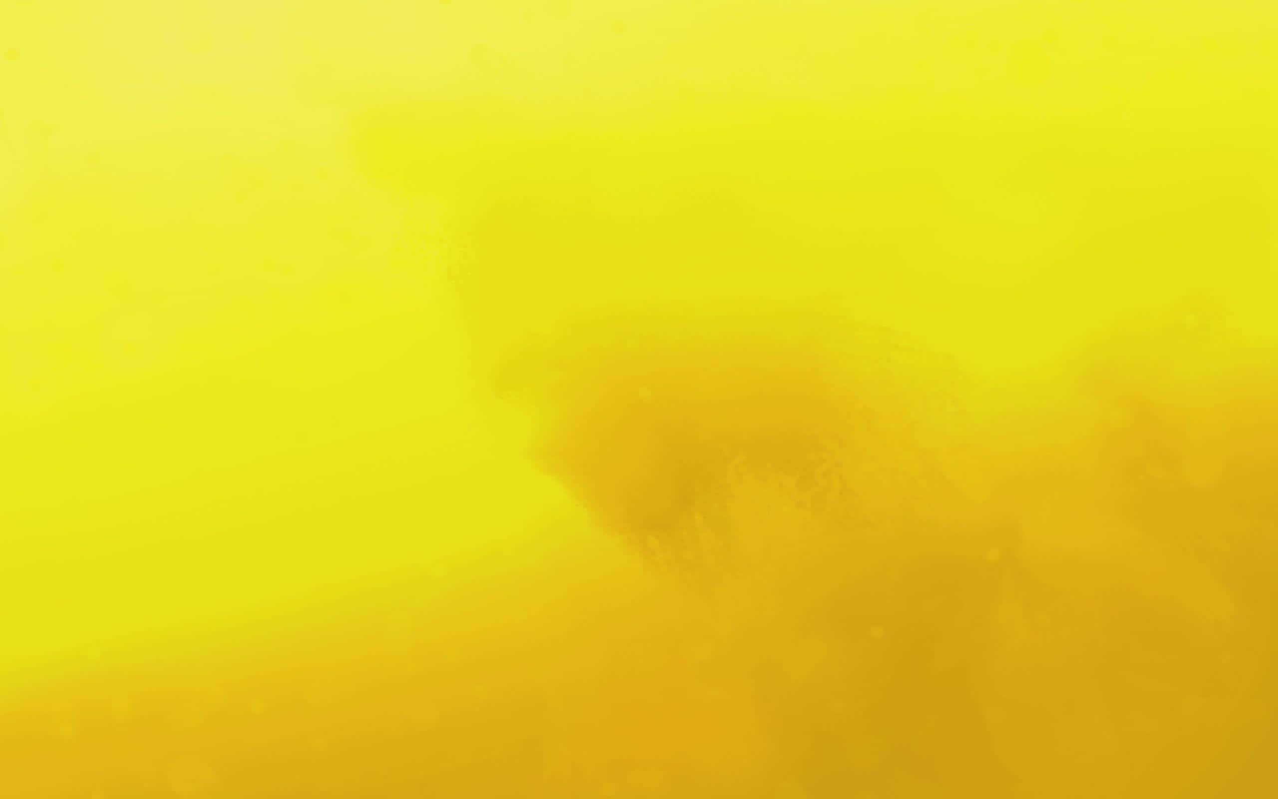 Cool Yellow 桌布 壁紙 — 柔和的金黃色漸變，帶有微妙的深色漩渦和漂浮粒子，營造出夢幻般的抽象背景。
