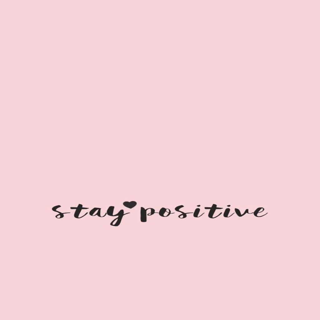 Positive 桌布 壁紙 — 柔和粉紅色背景，黑色草書文字寫著「stay positive」，並以心形取代字母「o」。