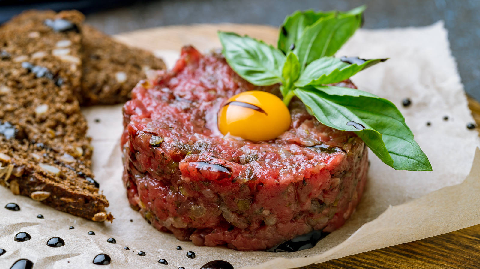 高級牛肉他他配鵪鶉蛋和羅勒，放在牛油紙上，附有麵包。