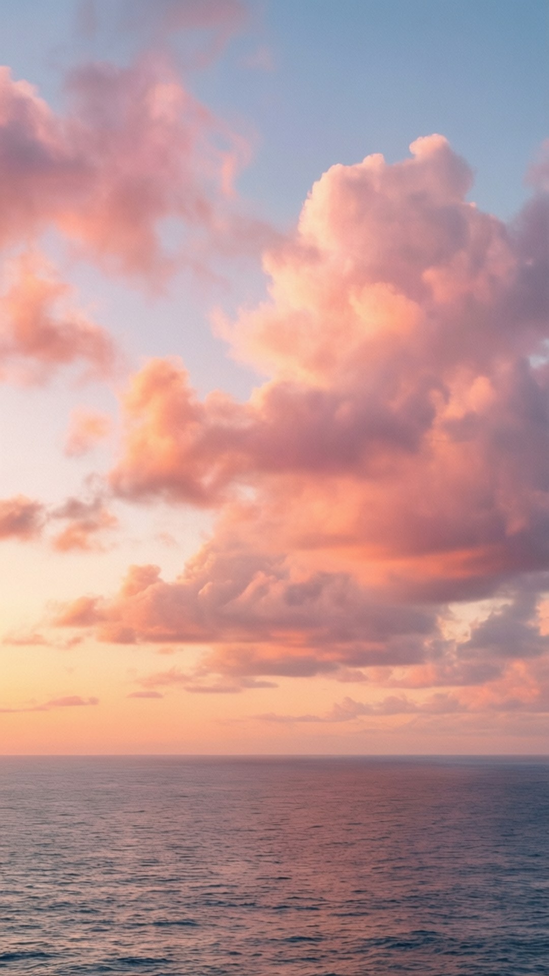 柔粉夕照雲霞 壁紙 — 廣闊的海洋與天空相遇，天空被塗上柔和的粉紅、橙色和藍色調，雲朵在日落時發光。