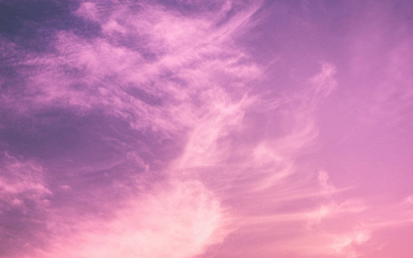 粉紅色和紫色的天空，帶有在日落時發光的縷縷雲彩