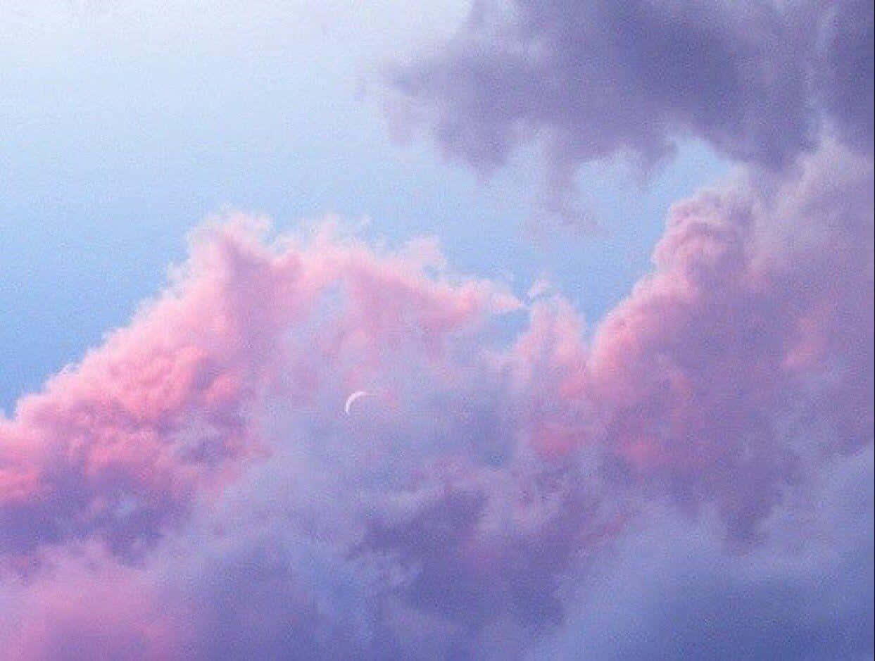 暮色中粉紅色和紫色雲層後的新月。