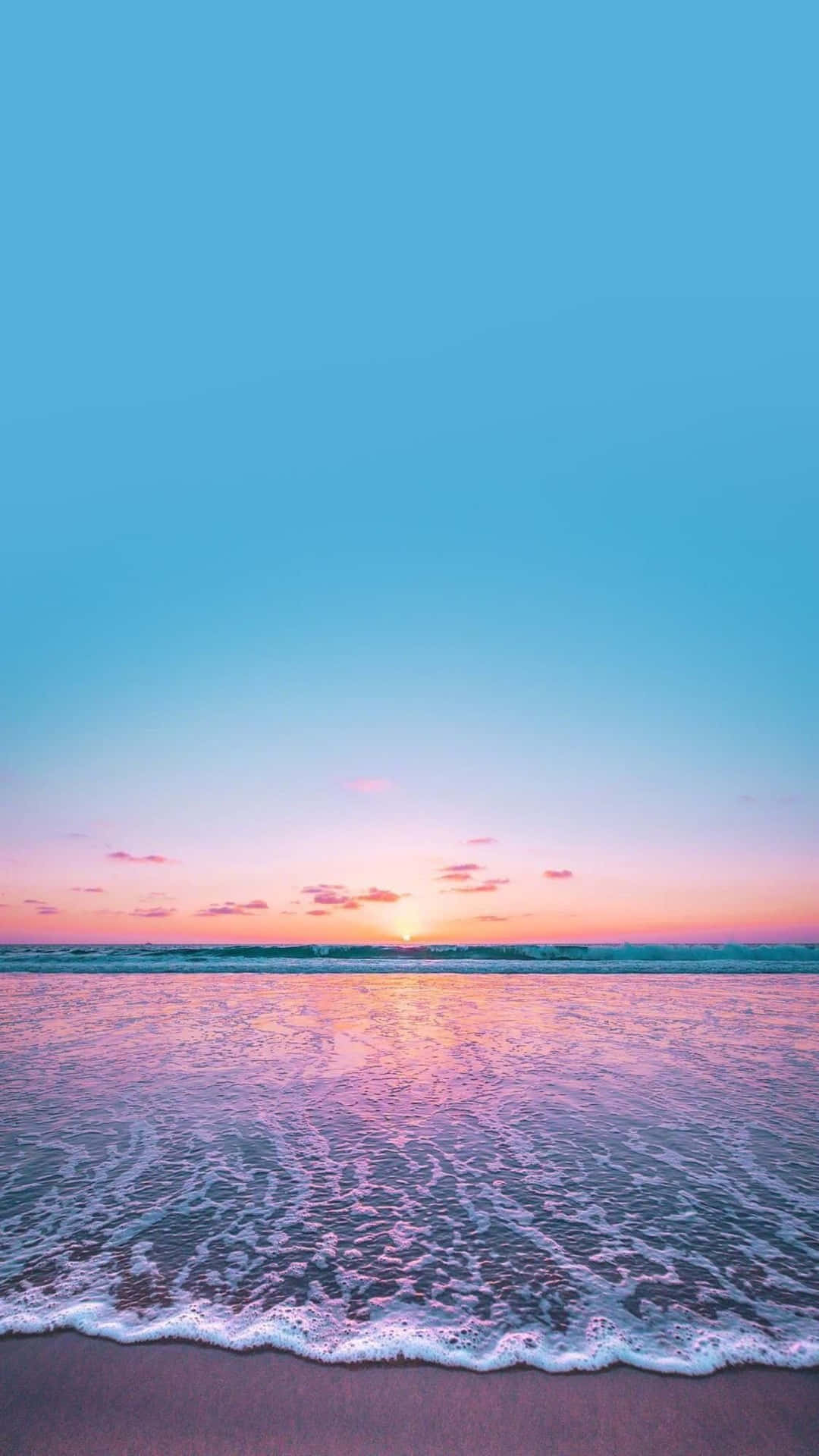 海洋上的夕陽，帶有粉紅色和藍色色調，沙灘上有溫柔的海浪。