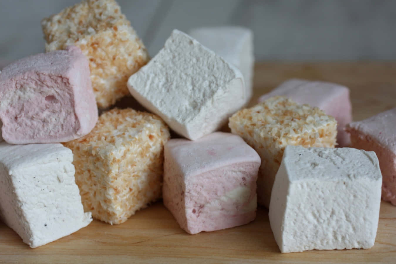 Marshmallow 桌布 壁紙 — 柔軟嘅粉彩色棉花糖，外層裹上椰子，堆疊喺木質表面上。